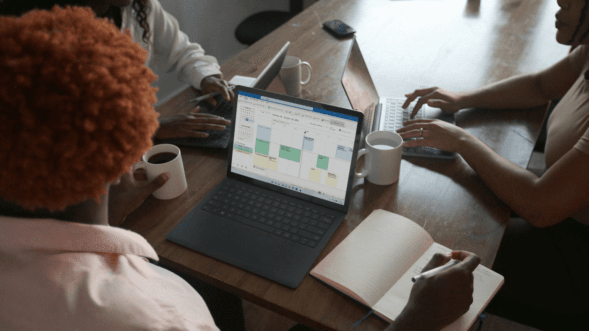 People collaborating around a laptop -  How to Automate Reconciliations in Excel
