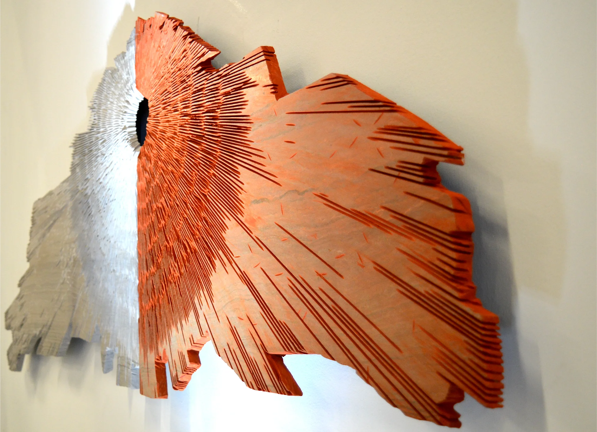 Installazione iStone Arte con blocco di pietra rossa lavorata e opera murale radiale contemporanea, sinergia tra arte materica e design per brand