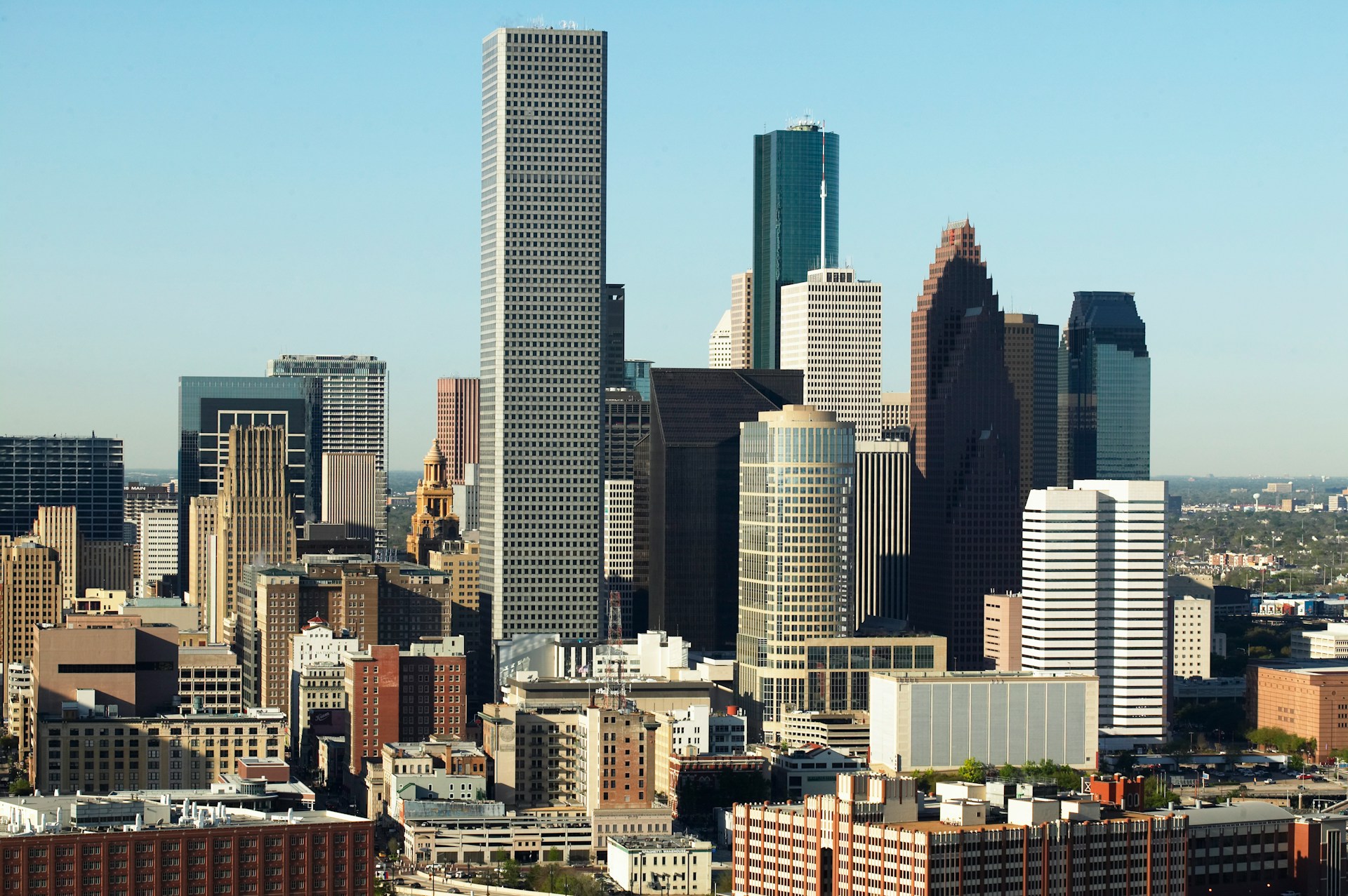 Downtown skyline of closely spaced high-rise office towers under a clear blue sky.