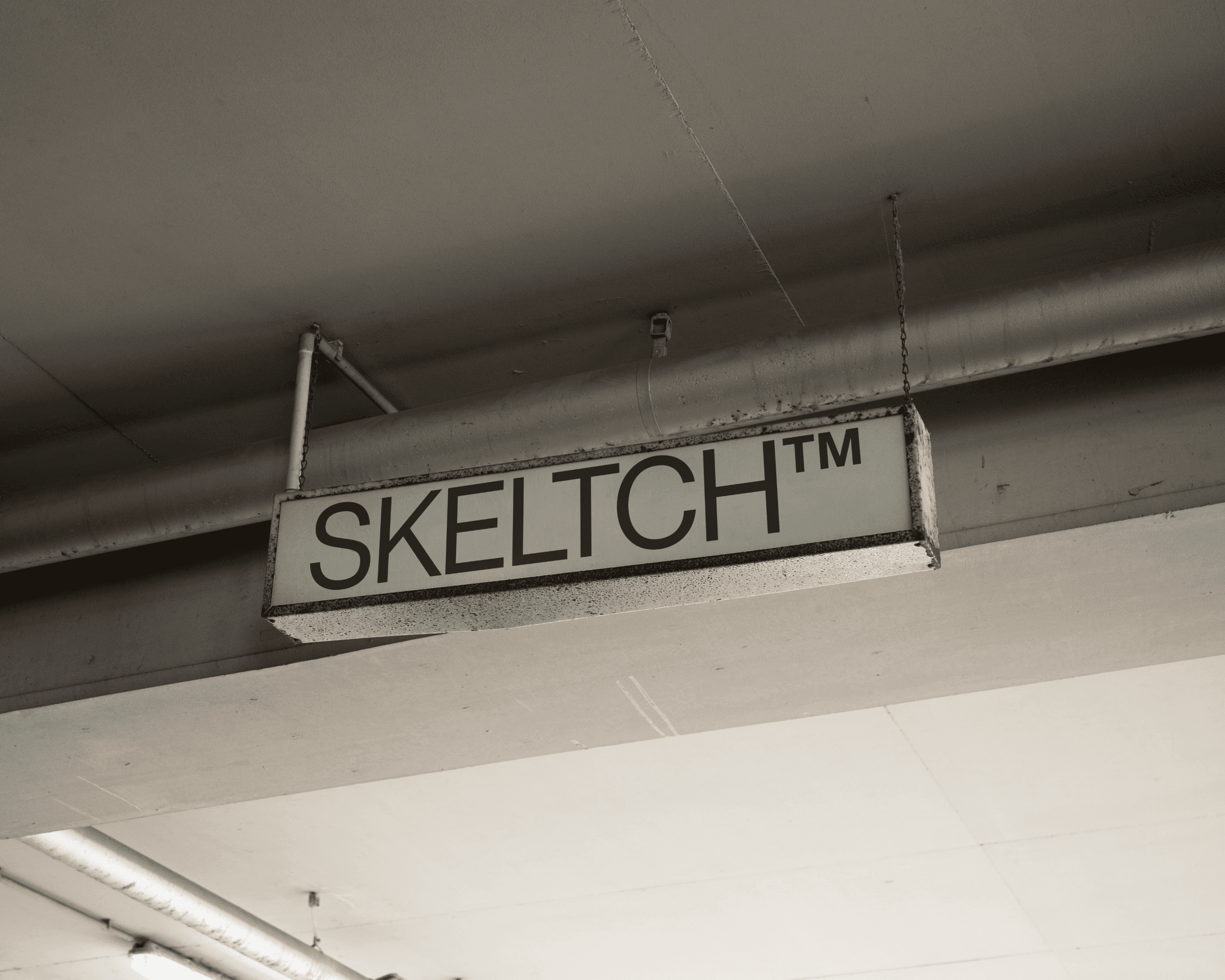A rusted sign hanging from a ceiling. The sign has the brand name SKELTCH™ on it.