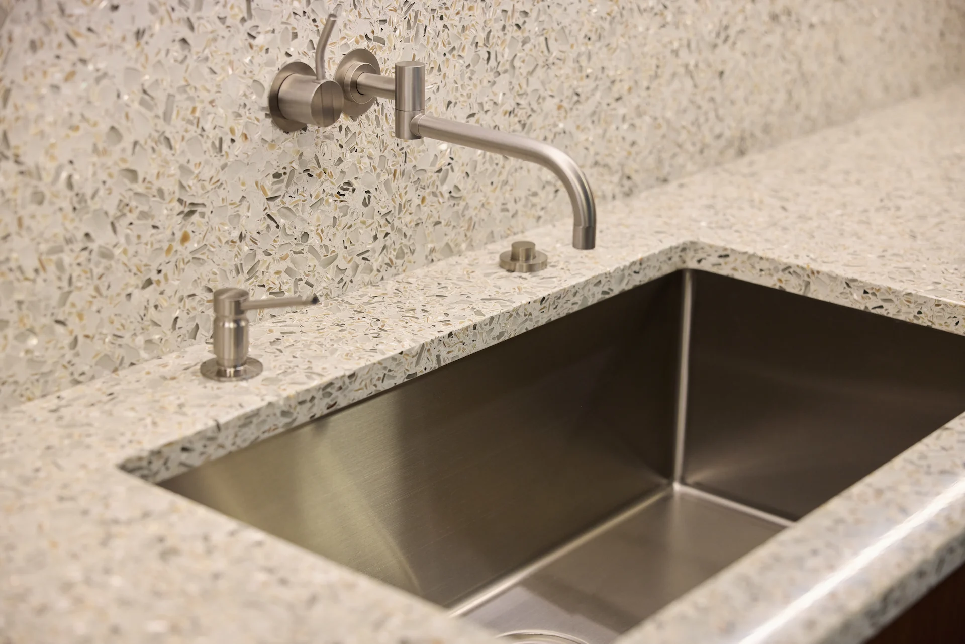 Close-up of the kitchen sink set in a terrazzo countertop, showcasing the unique materials and modern design choices in the Fairhills Eichler Tract remodel. Photo by Todd Huge.