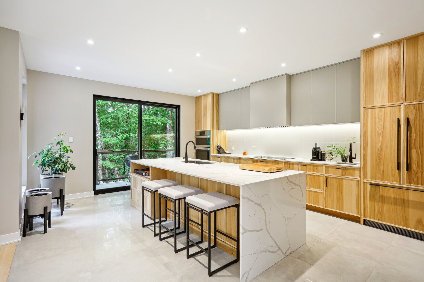 Cuisine contemporaine, grand îlot et porte-patio vers la terrasse.