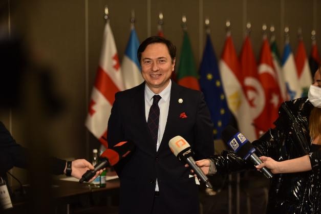 Aerial view of a winding road surrounded by dense green and yellow trees, showcasing nature’s vibrant colors.