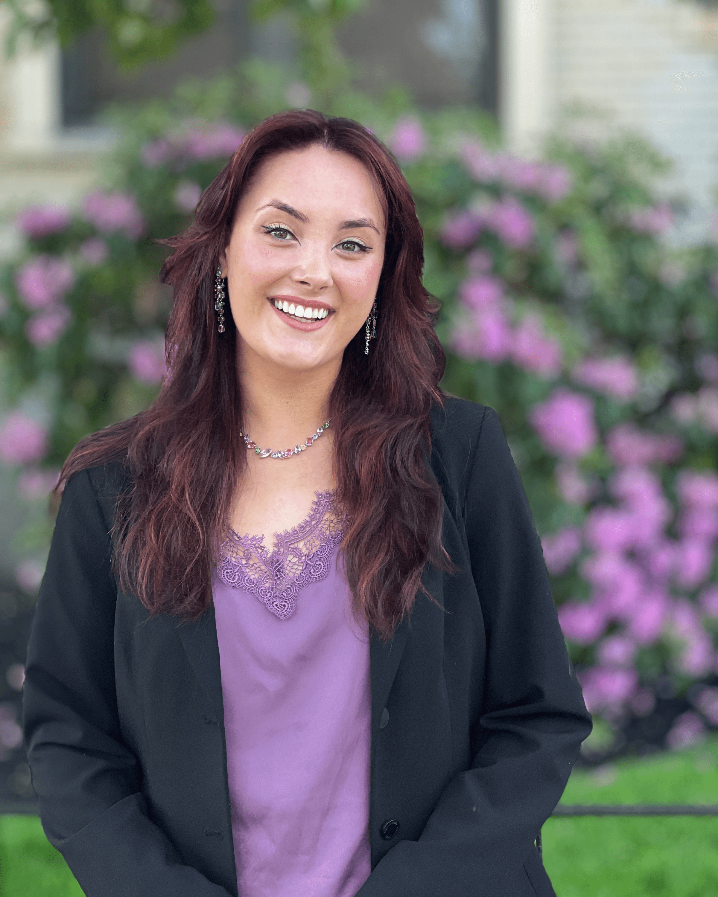 A young person with long, wavy hair sits in front of a plain background, looking directly at the camera.