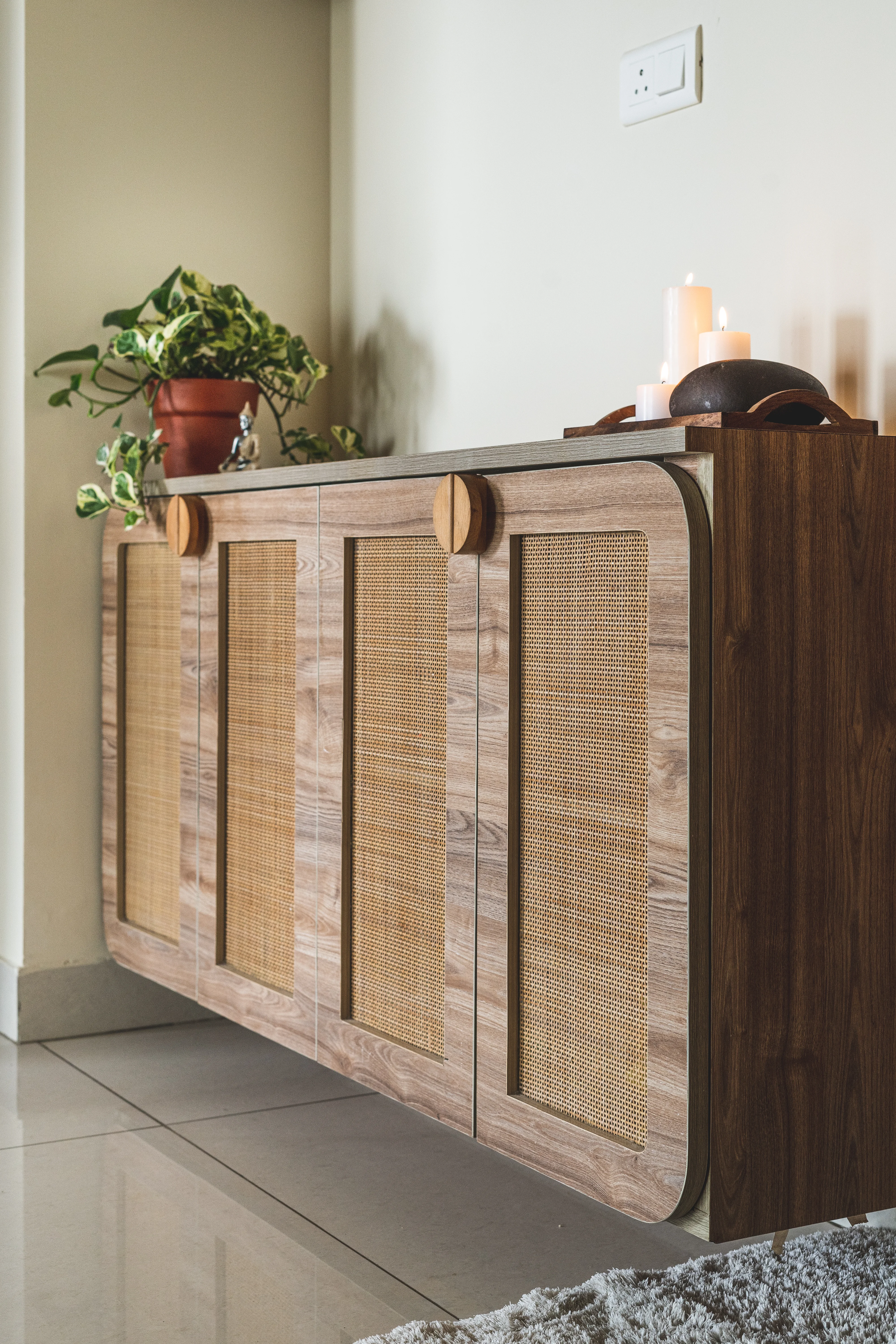A wooden cabinet with glass doors displaying a plant, highlighting minimalistic design for South Indian interiors.