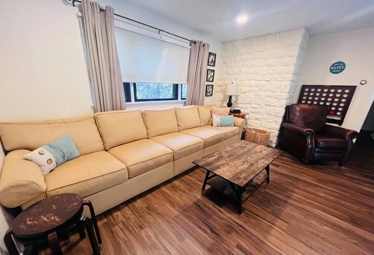 Family room with long cream sofa, leather recliner and wood coffee table at Relax in Style