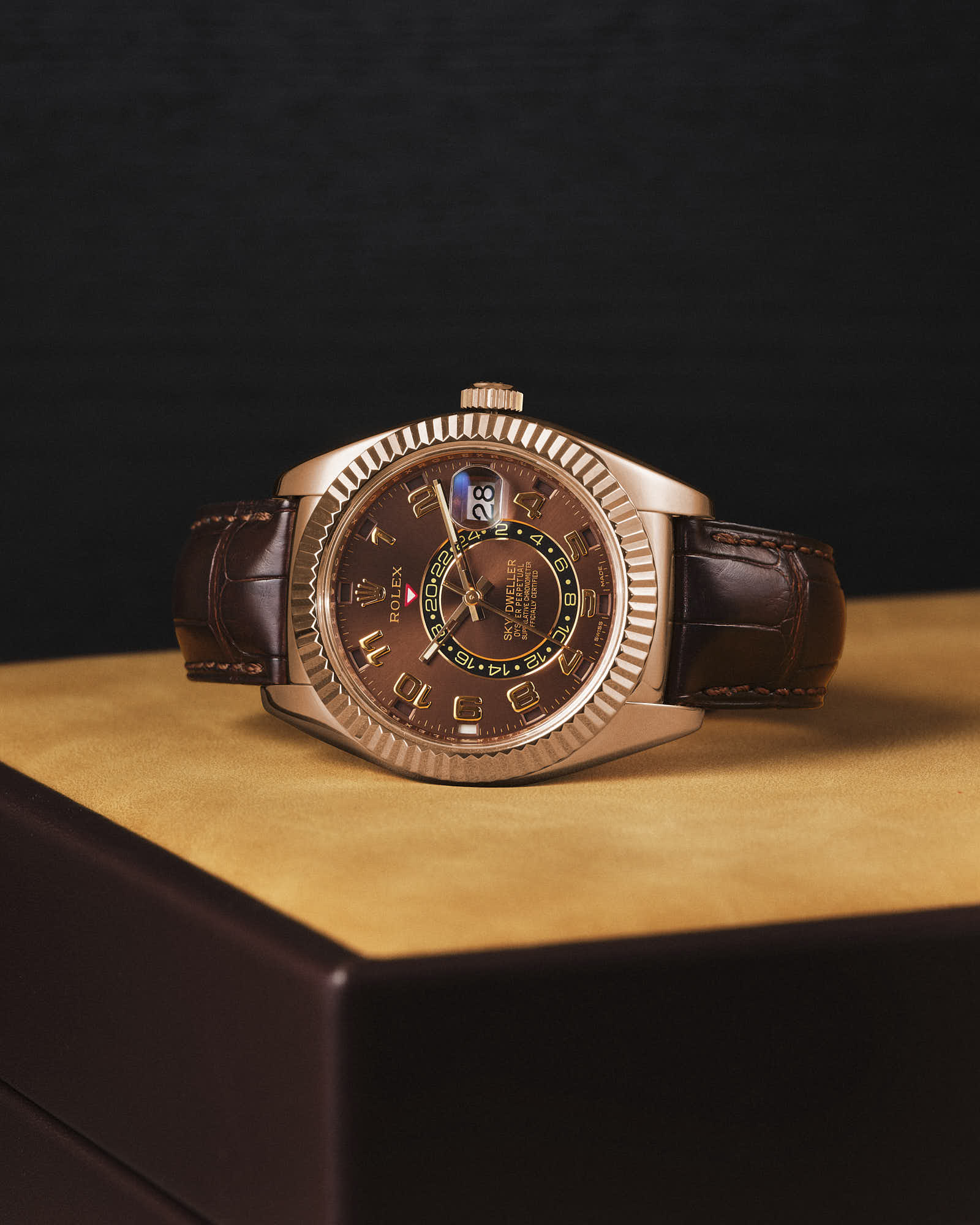 Luxury brown leather watch with gold accents on dark background.