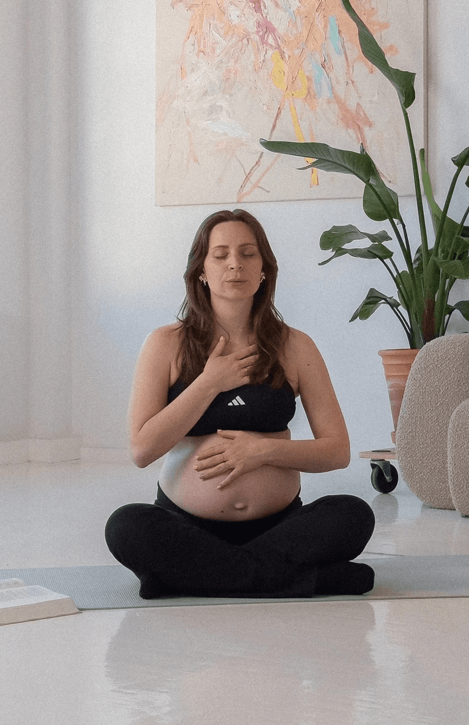 A woman sits cross-legged with eyes closed, wearing a white blouse and a long purple skirt, looking serene.