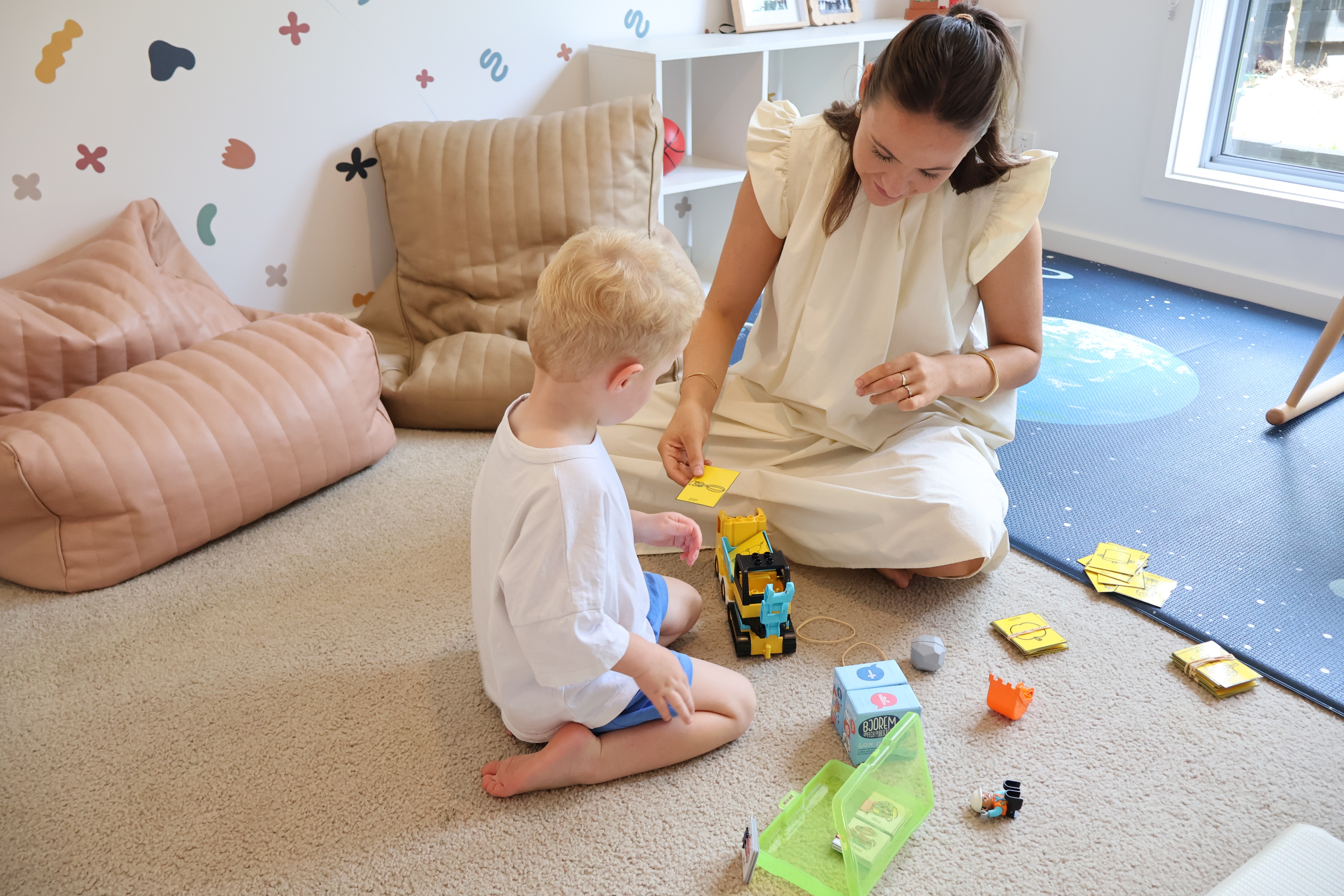 Young boy and Speech Pathologist playing with a toy truck during a speech therapy session.