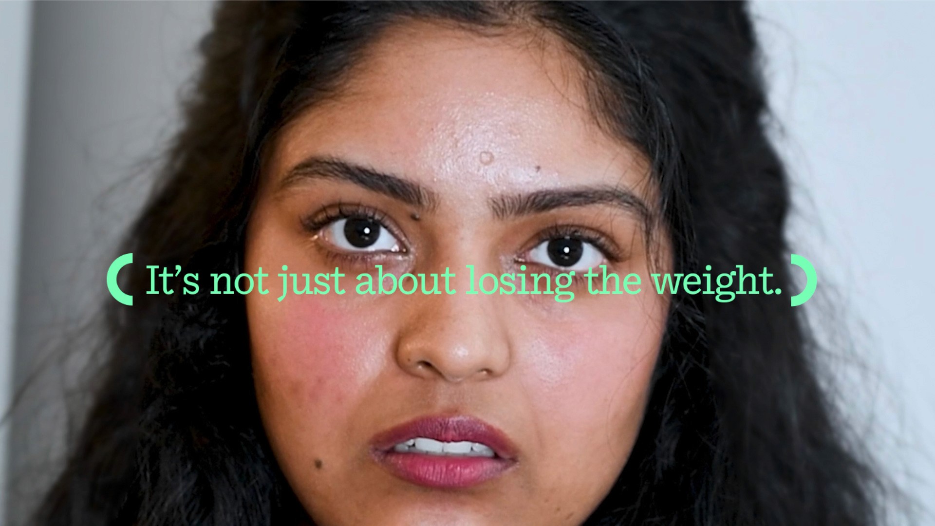 A close-up of a person's face with dark hair and brown skin. Their expression appears serious or slightly concerned. Green text overlaid on the image reads, "It's not just about losing the weight."