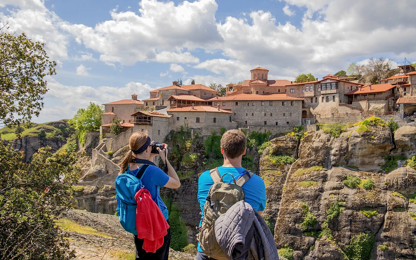 Gasten wandelen nabij het klooster van Meteora, Griekenland, en leggen daarbij prachtige uitzichten vast.
