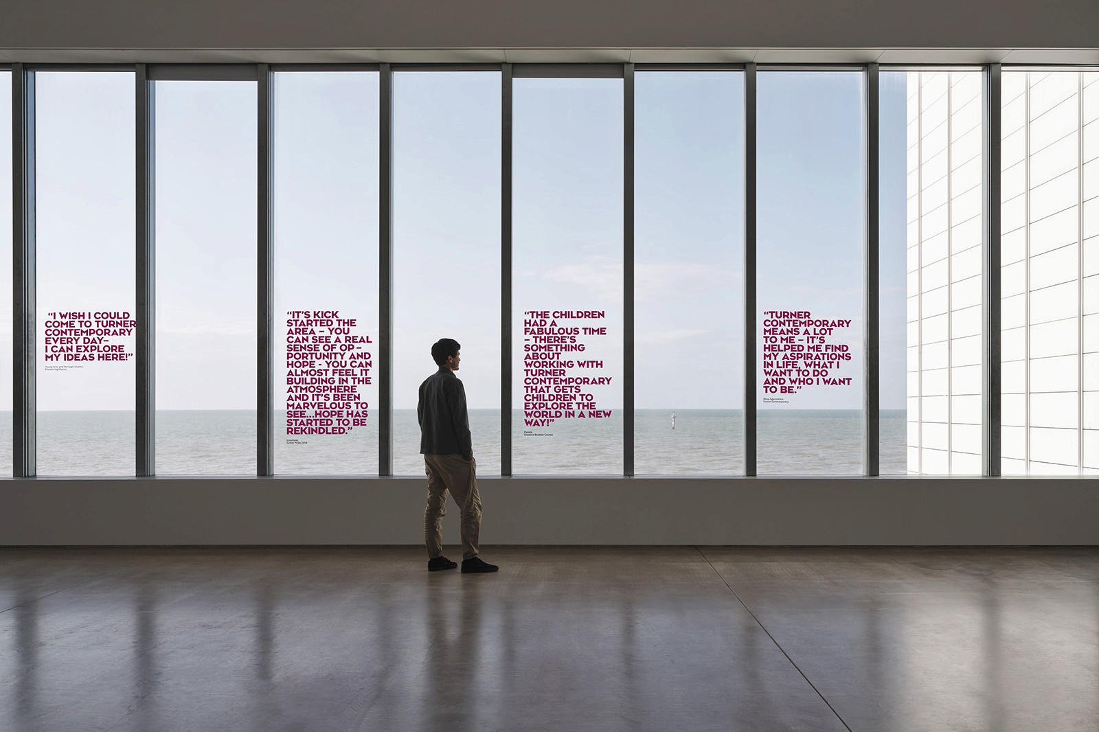 A person stands in front of large windows with a view of a landscape, reflecting a calm and modern environment.