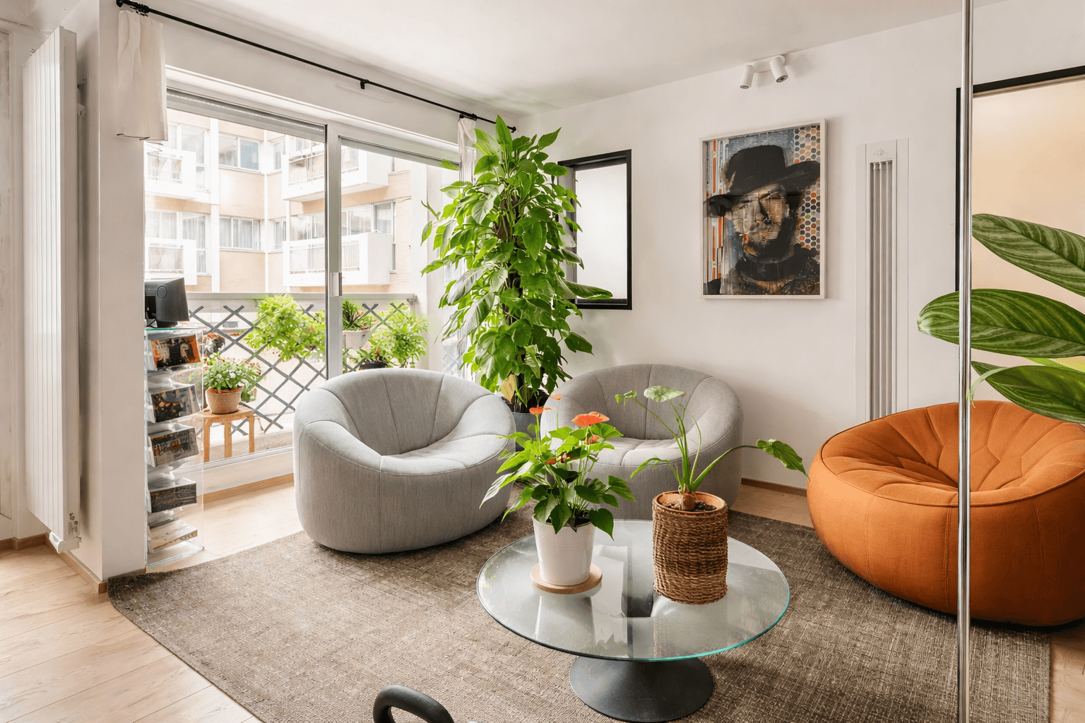Cozy living room with armchairs, plants, art, and a balcony view. Bright, modern interior design.