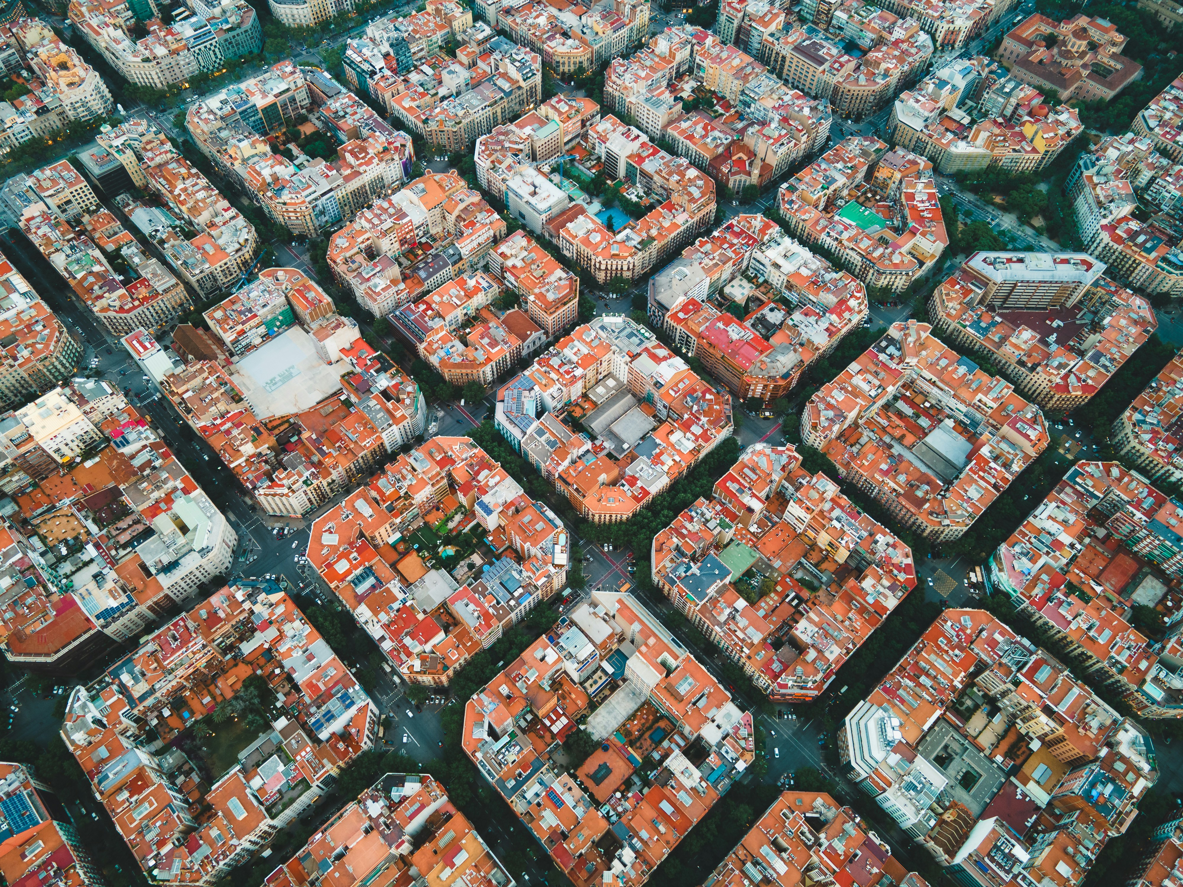 An aerial image of the Eixample neighborhood of Barcelona, with perfectly uniform city blocks captured from above. 