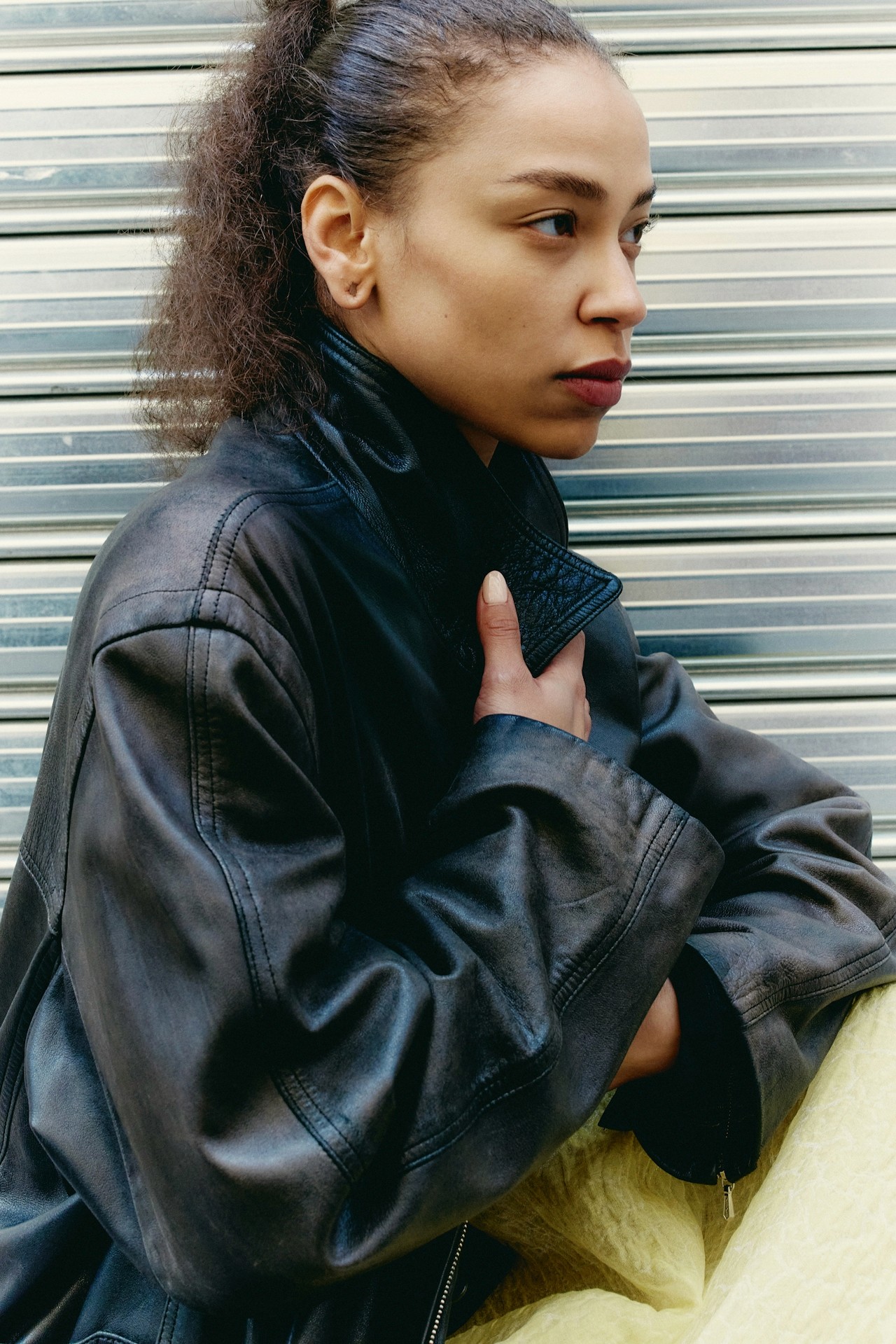 A woman in a leather jacket looking to the side against a textured background.