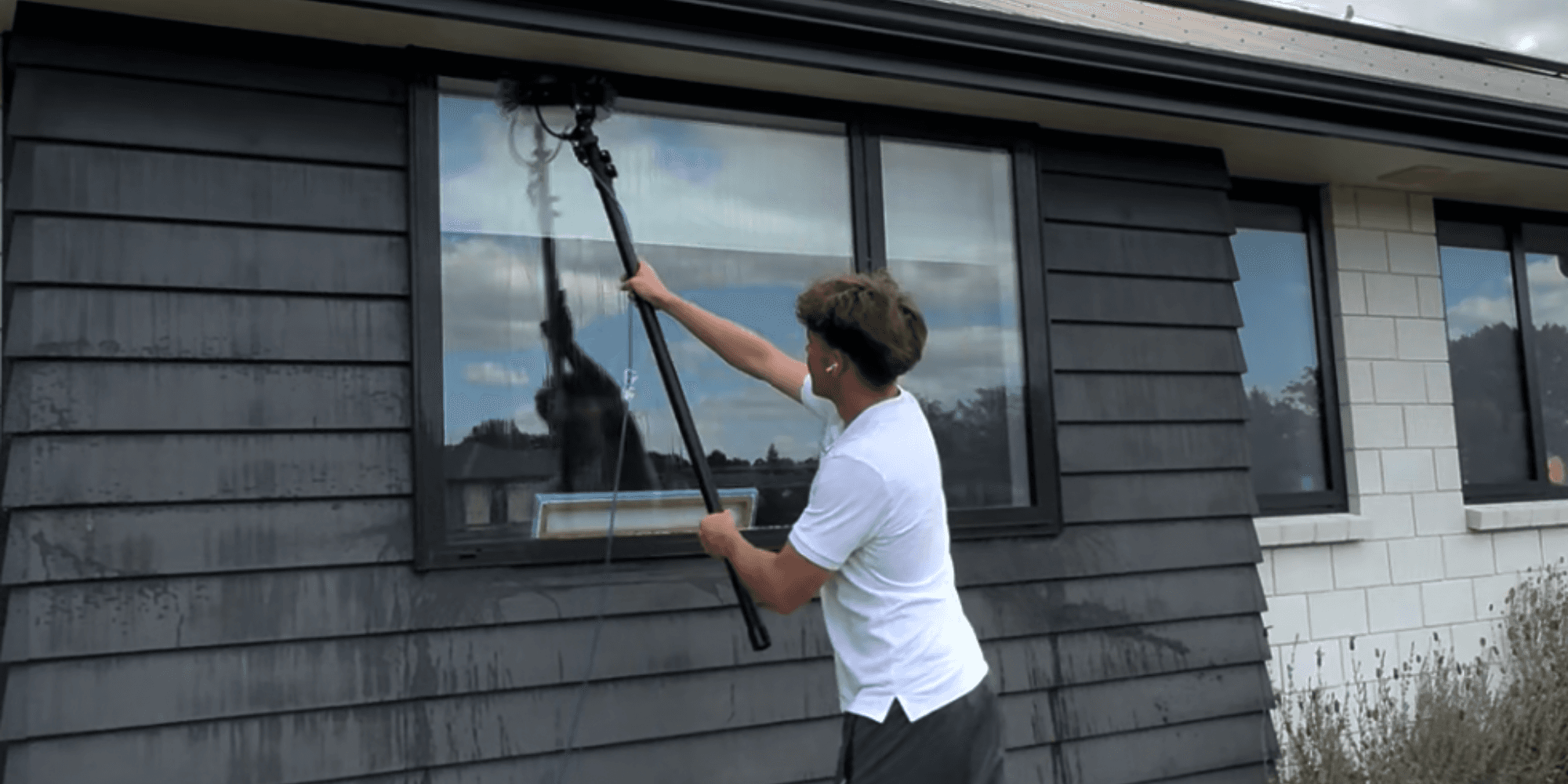 Max cleaning exterior windows on a Hamilton home using a water-fed pole system
