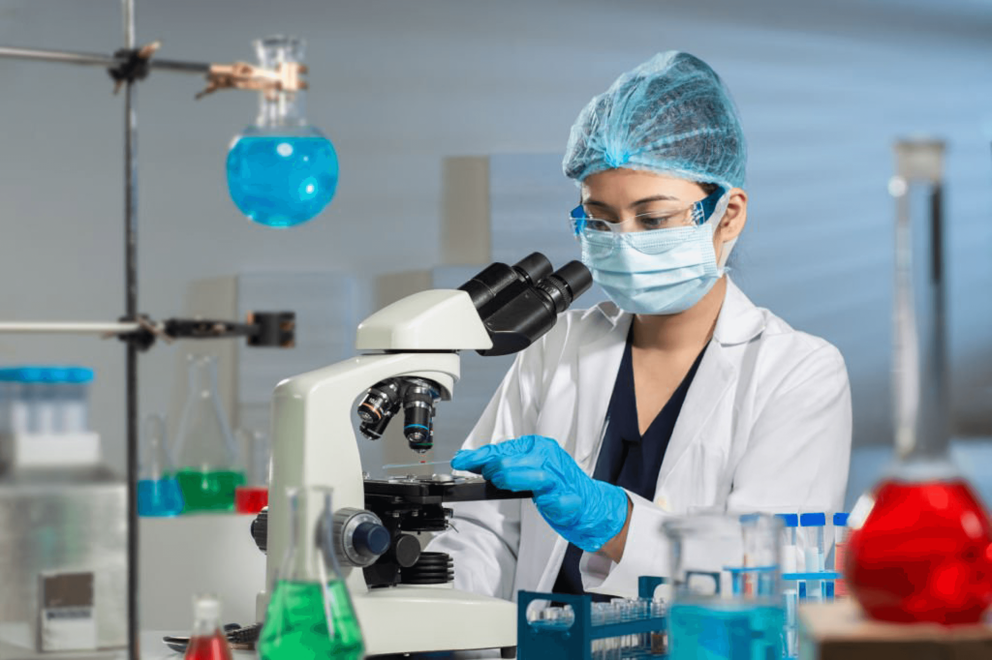 Woman in a laboratory wearing safety gear and using a microscope, highlighting women in medical research and scientific innovation.