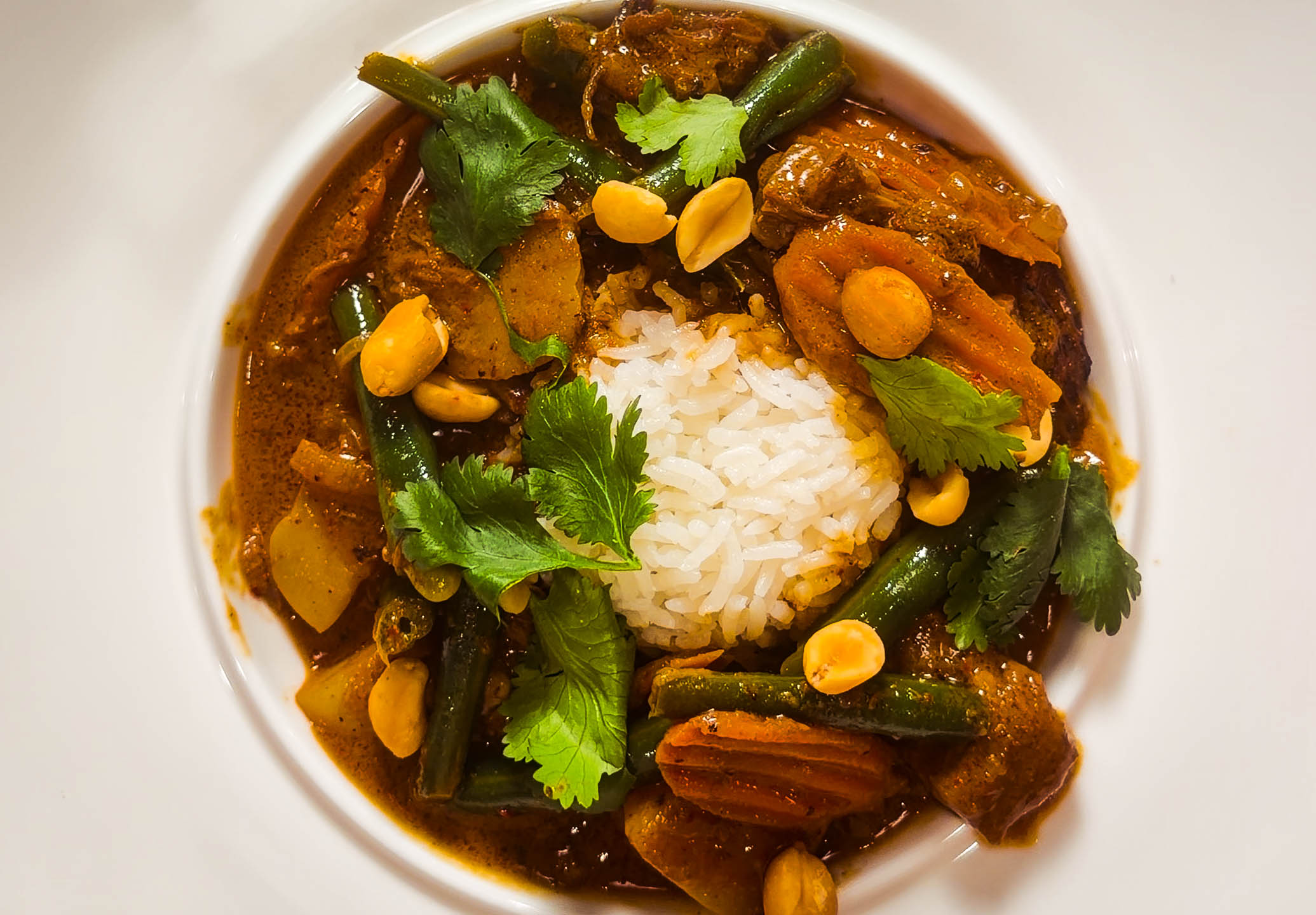 an overhead shot of massaman curry in a white dish