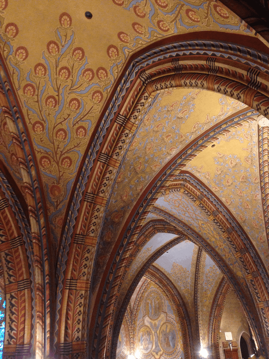 Interior of a church's painted ceiling with arches and floral details 