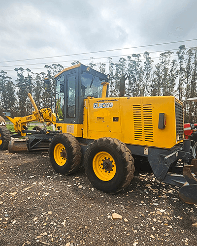 yellow excavator beside brown brick wall