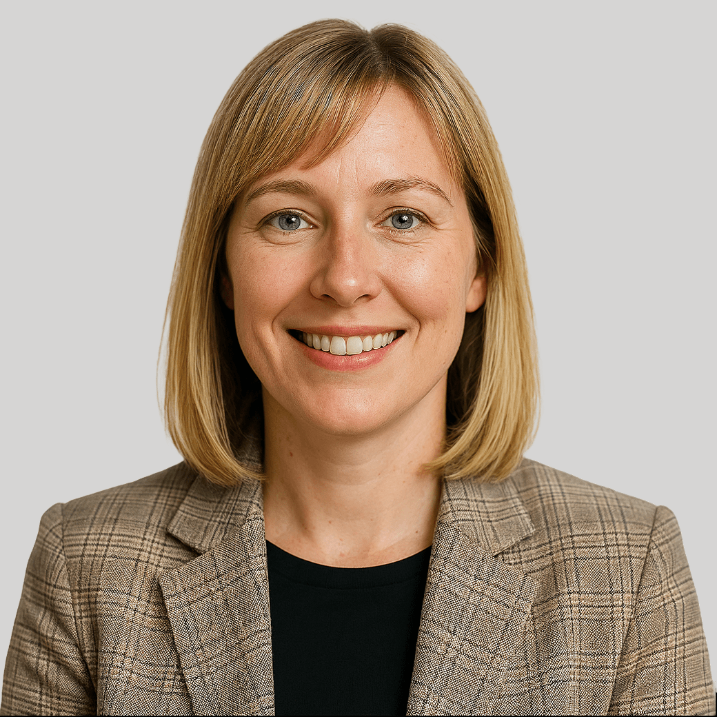 Portrait of a smiling woman with blonde hair wearing a plaid blazer.