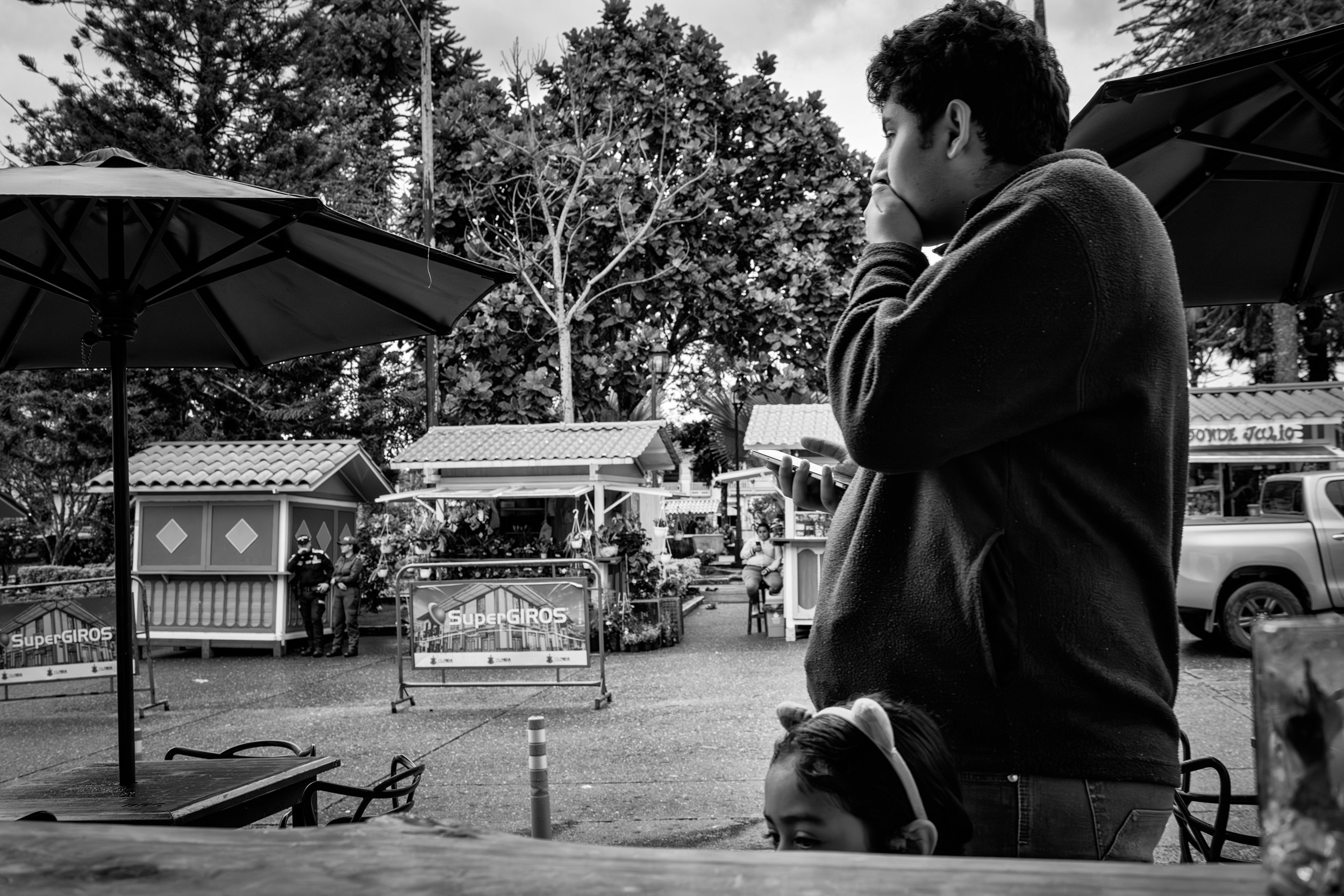 Rainy street scene with people passing by a bar window.