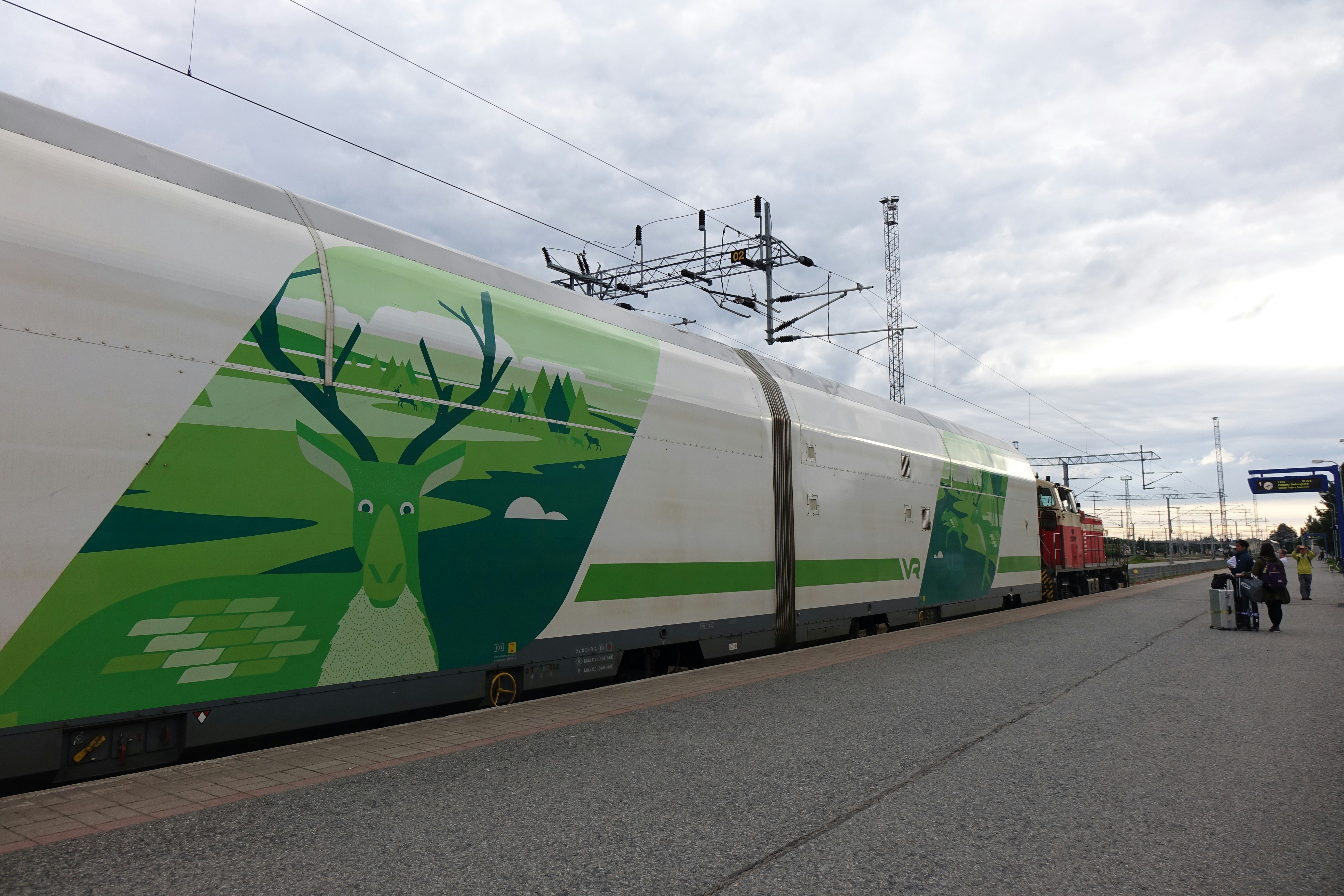 A green and white train traveling down train tracks
