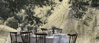 A charming outdoor table set on a hillside surrounded by nature, evoking intimacy, serenity, and rustic French elegance.  