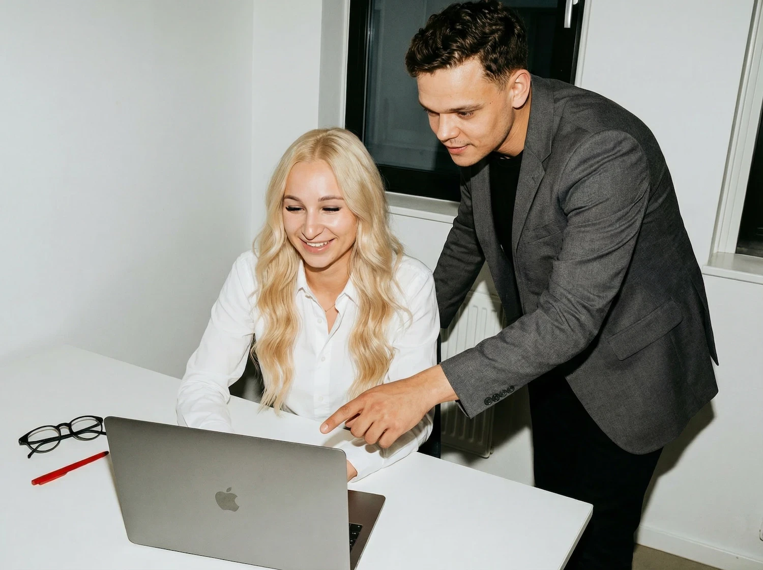 Two colleagues smiling while working together on a laptop.