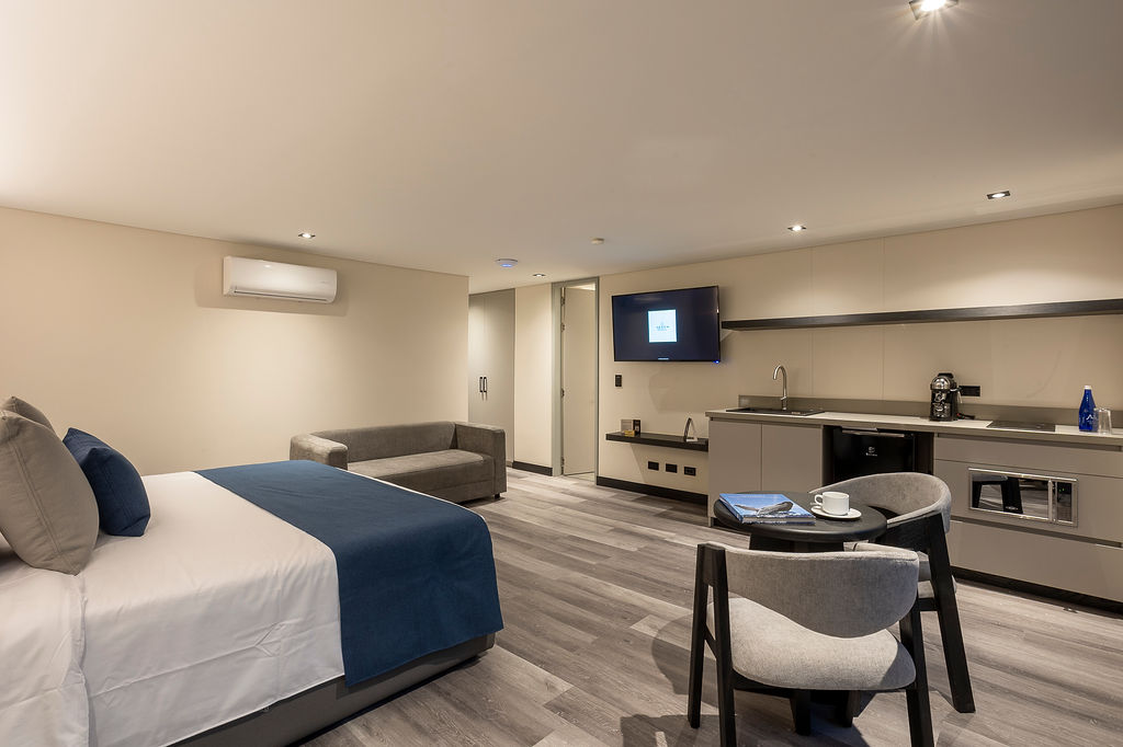 Habitación de lujo con cama king Medellín en Altus Hotel, con ventanales insonorizados y diseño elegante en Laureles.