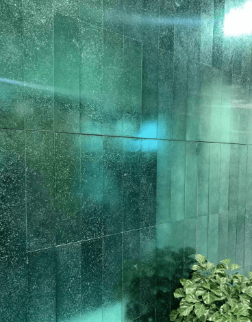 A wall made of electroplated green stone tiles, featuring a glossy and reflective surface with a luxurious feel.