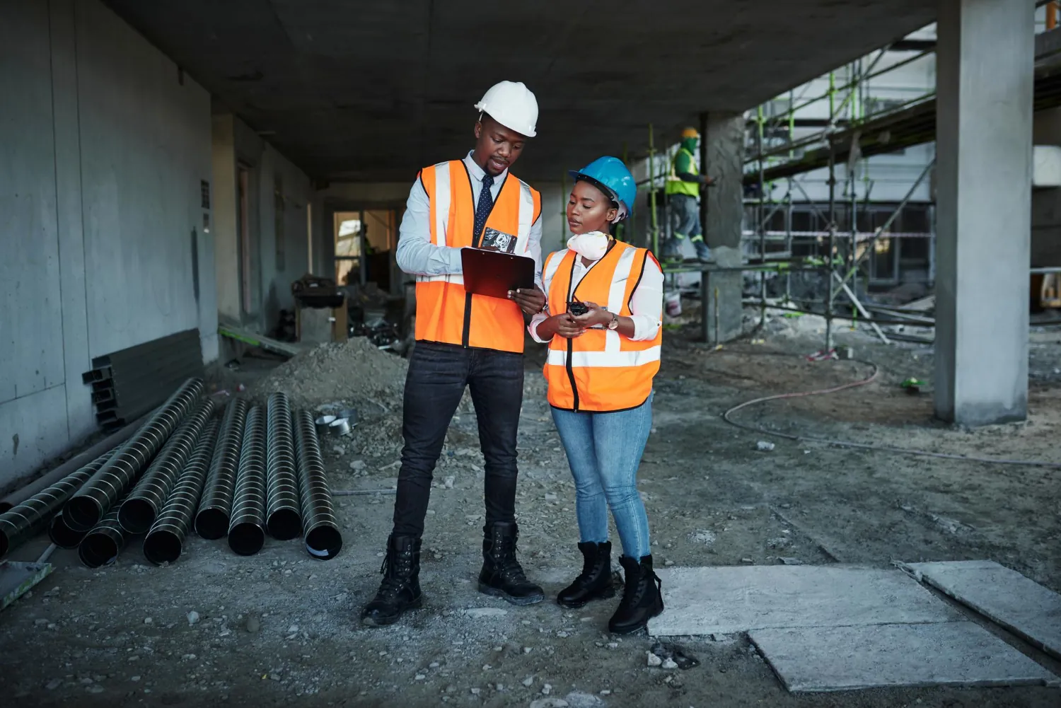 Engenheiros com equipamentos de segurança realizam visitas presenciais ao canteiro de obras para inspeção e acompanhamento.