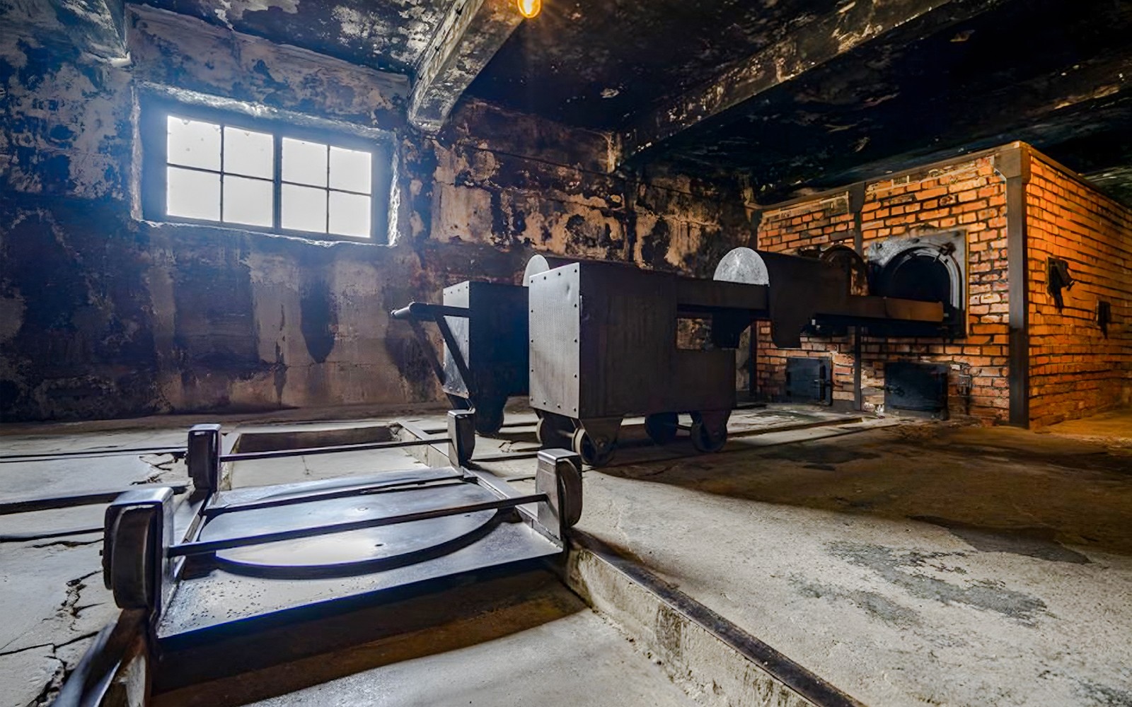 Inni í líkhúsinu í Auschwitz I, sem sýnir múrsteins ofna og málmkörfur.