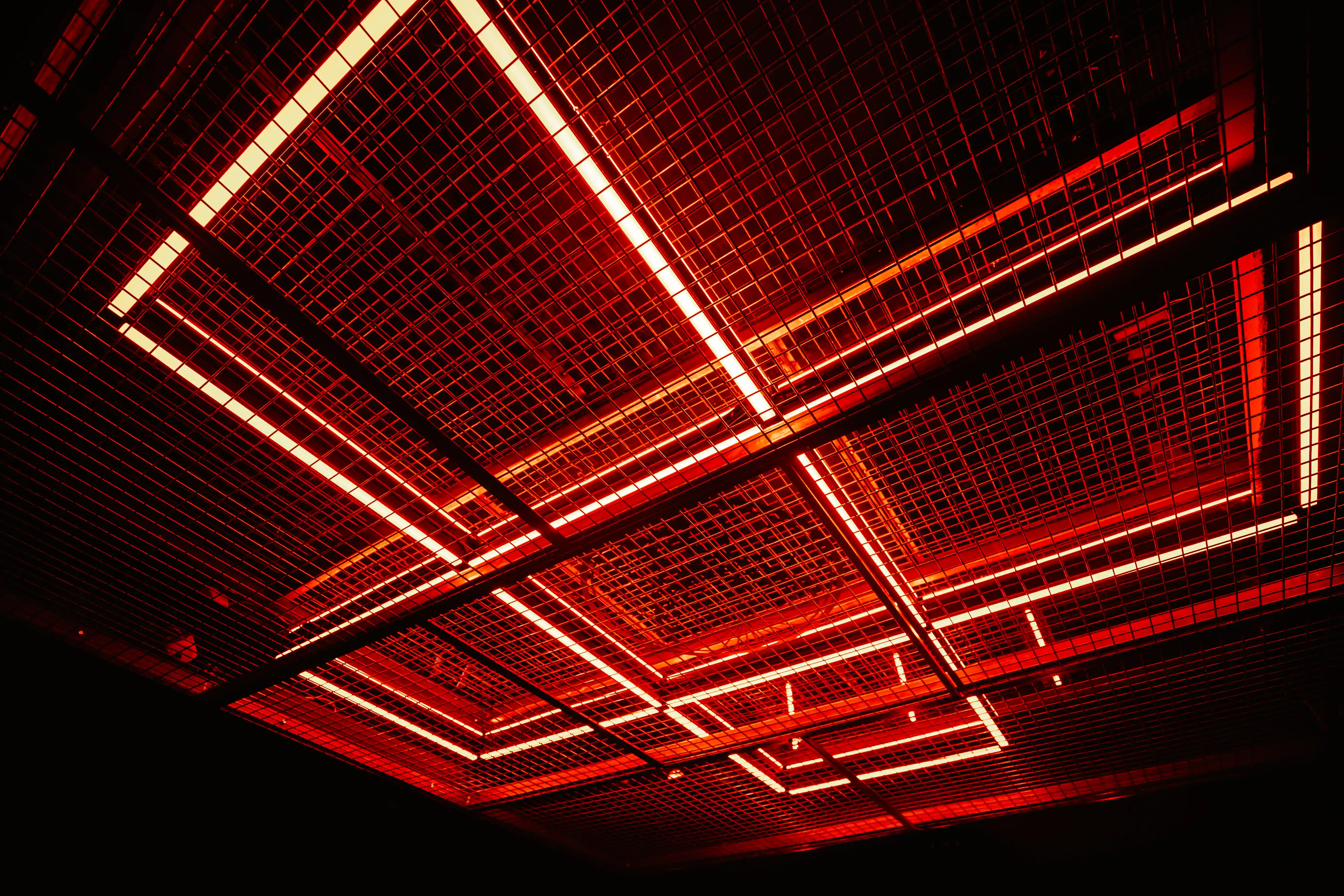 Ceiling installation at JÄGERMEISTER x CALL ME DRELLA made of suspended metal grid panels with red and white neon light lines in diamond patterns.