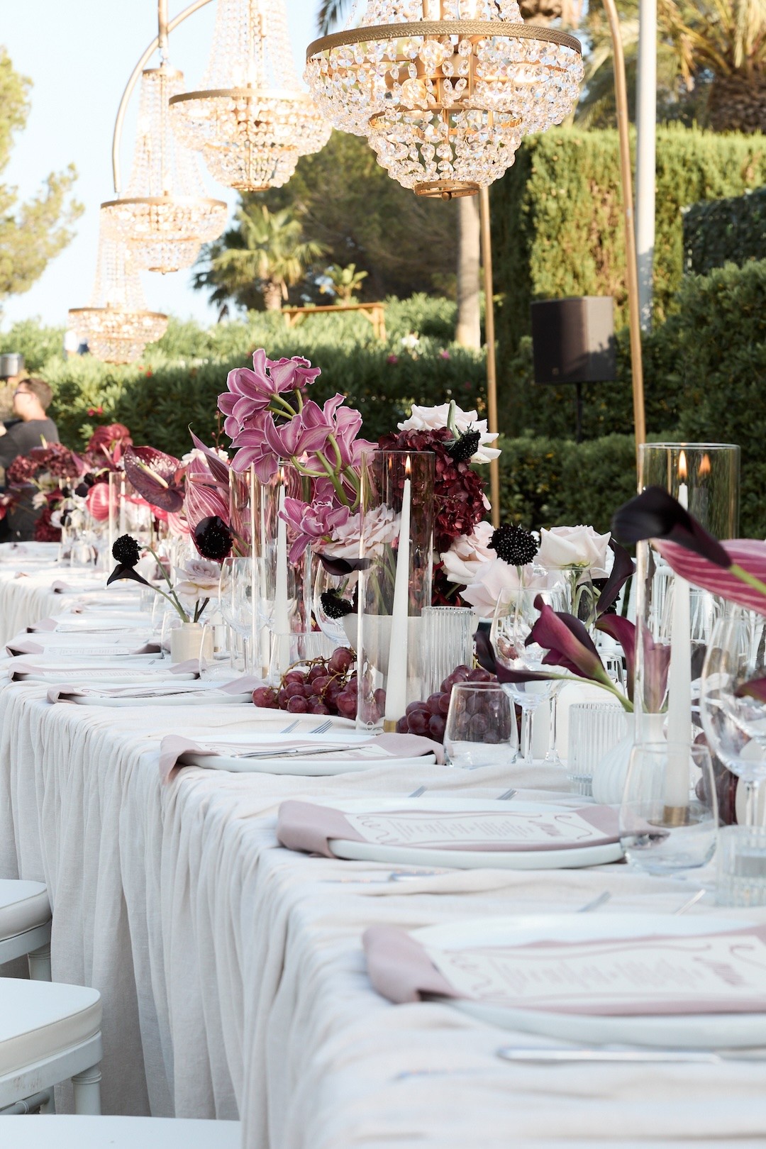 Elegant wedding table decorated with pink orchids and chandeliers in a garden in Ibiza.