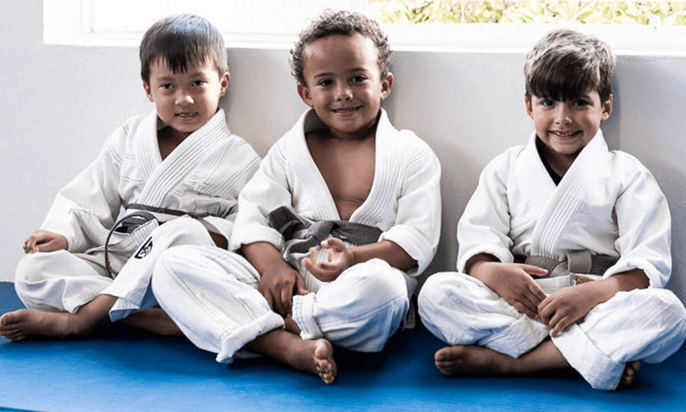 Toddlers children sitting in a line wearing white gis