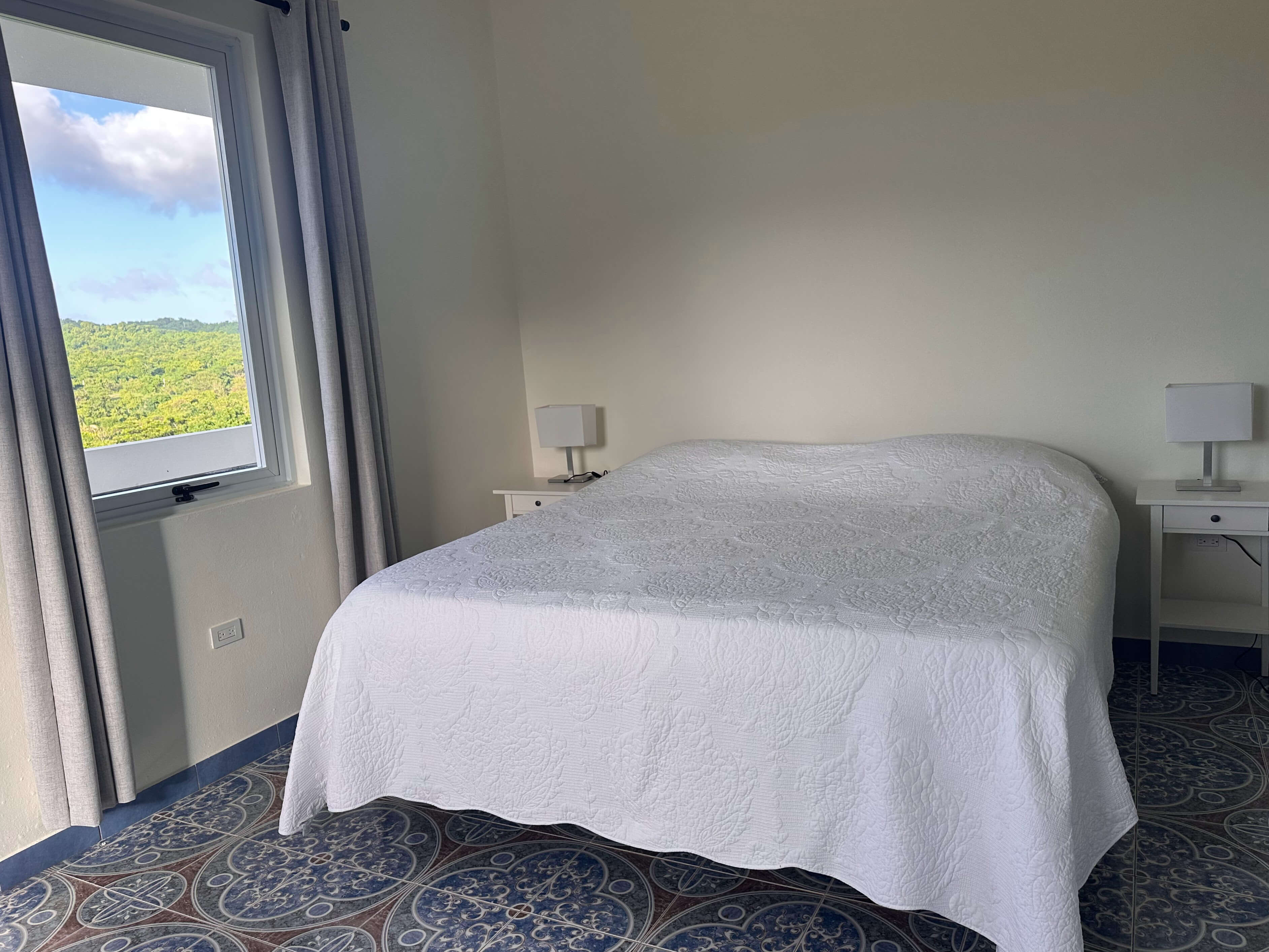 King bed in Room 7 at Club Vieques with a view of tropical landscape.