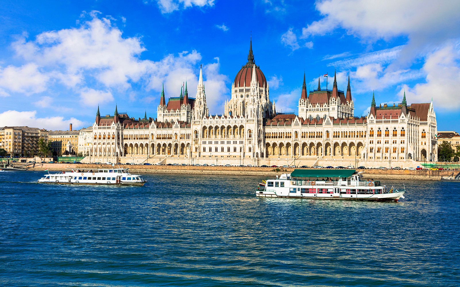 Danube River cruise boats passing the Hungarian Parliament Building in Budapest.