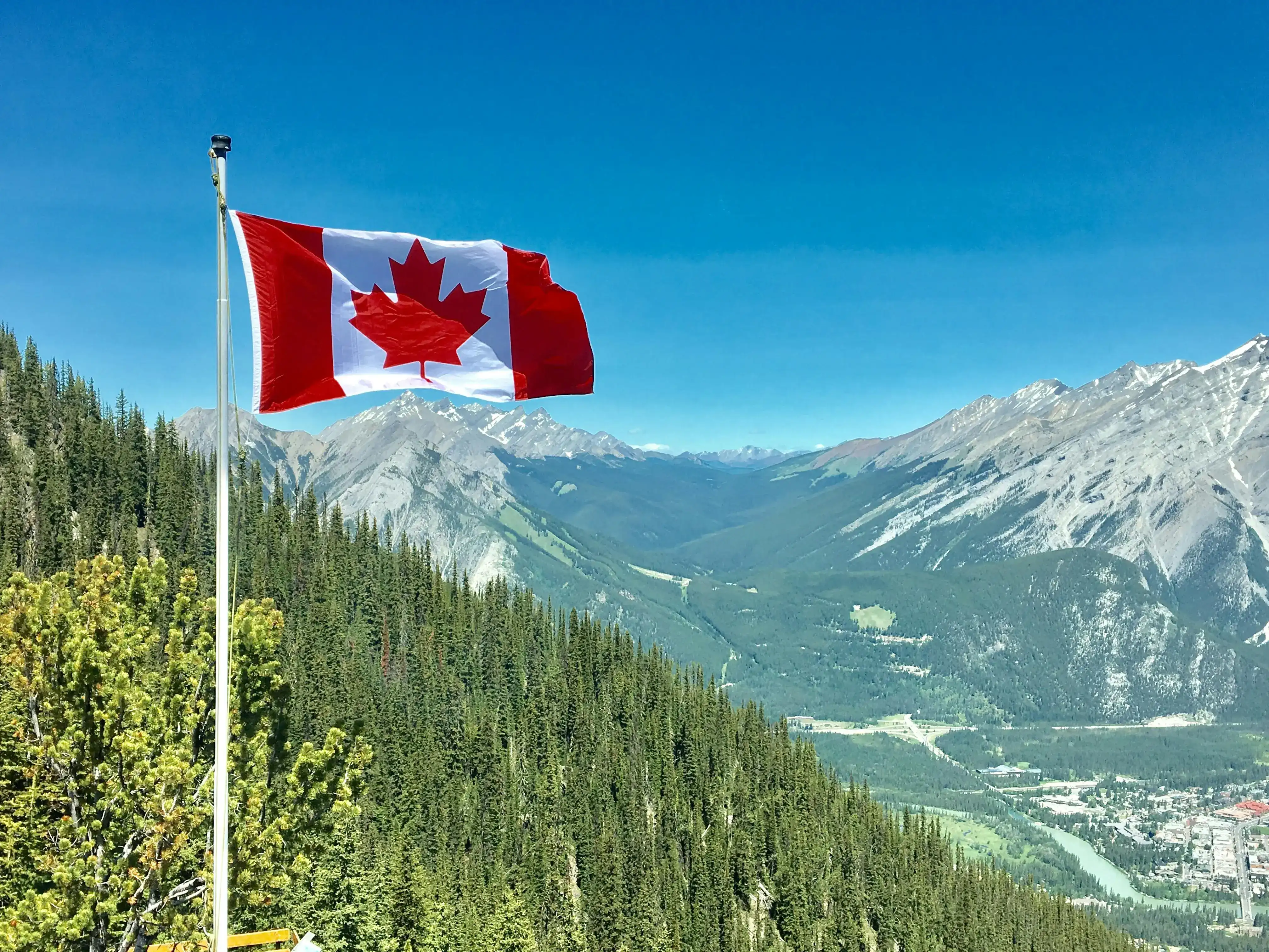 canada flag in front of a mountainous scenery