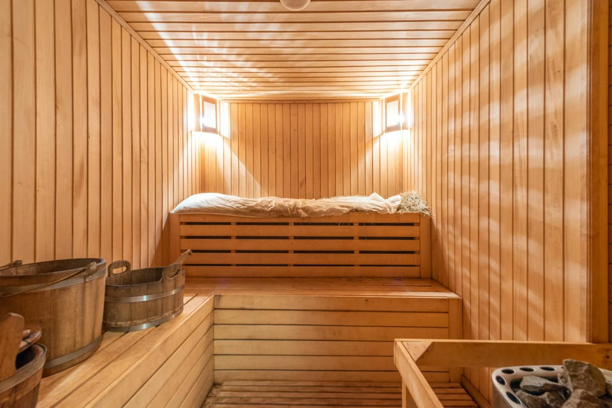 Intérieur de sauna en bois avec seau et banc pour relaxation.