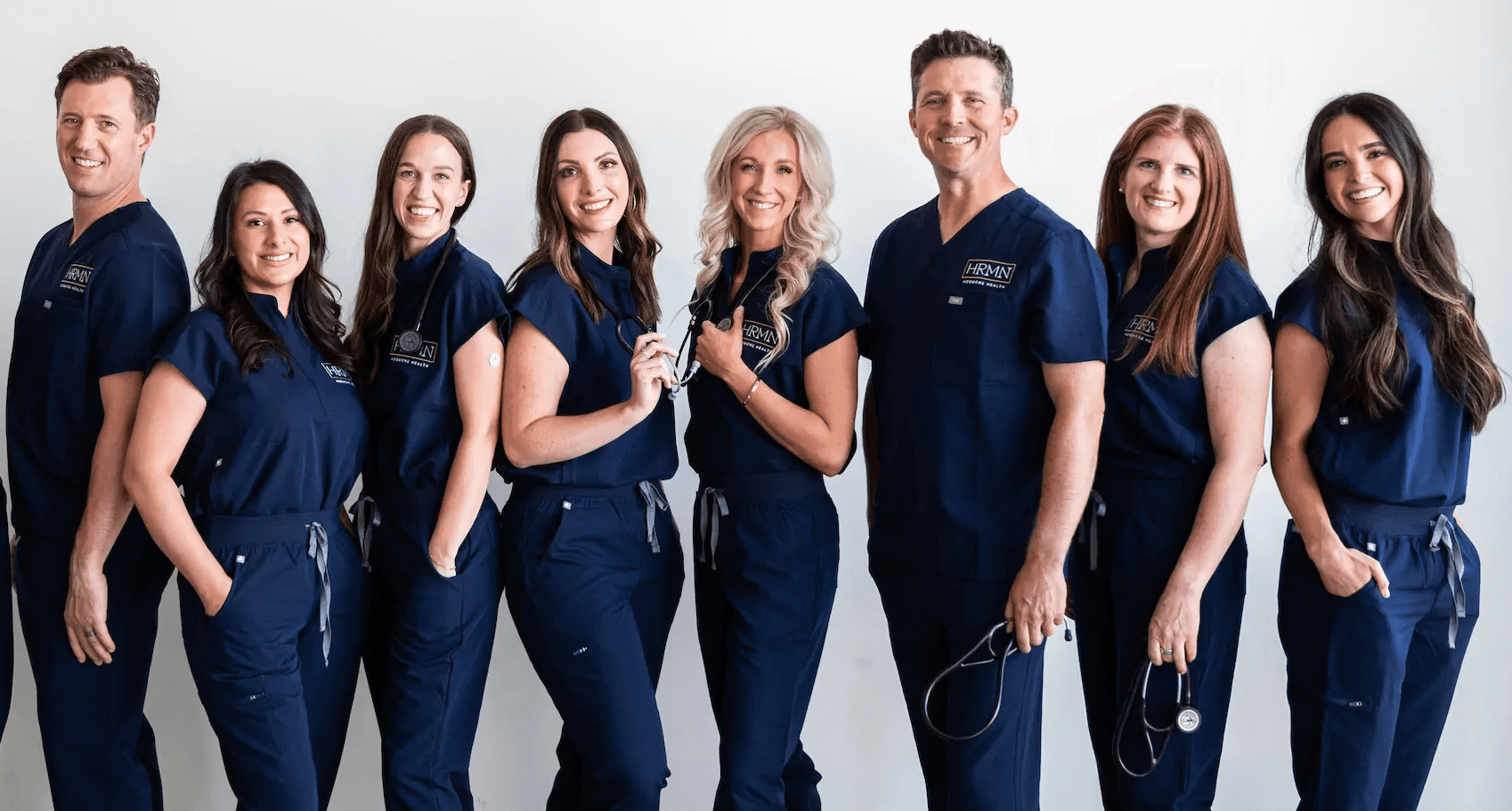 Group photo of the HRMN Health team, including Jamie Ruiz, Chelsey Galipeau, and two other employees, wearing blue scrubs in a professional medical setting.