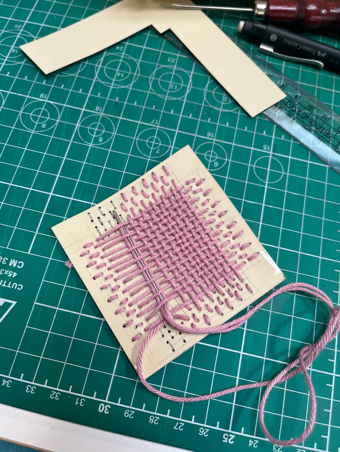 Darning with yarn on cardboard