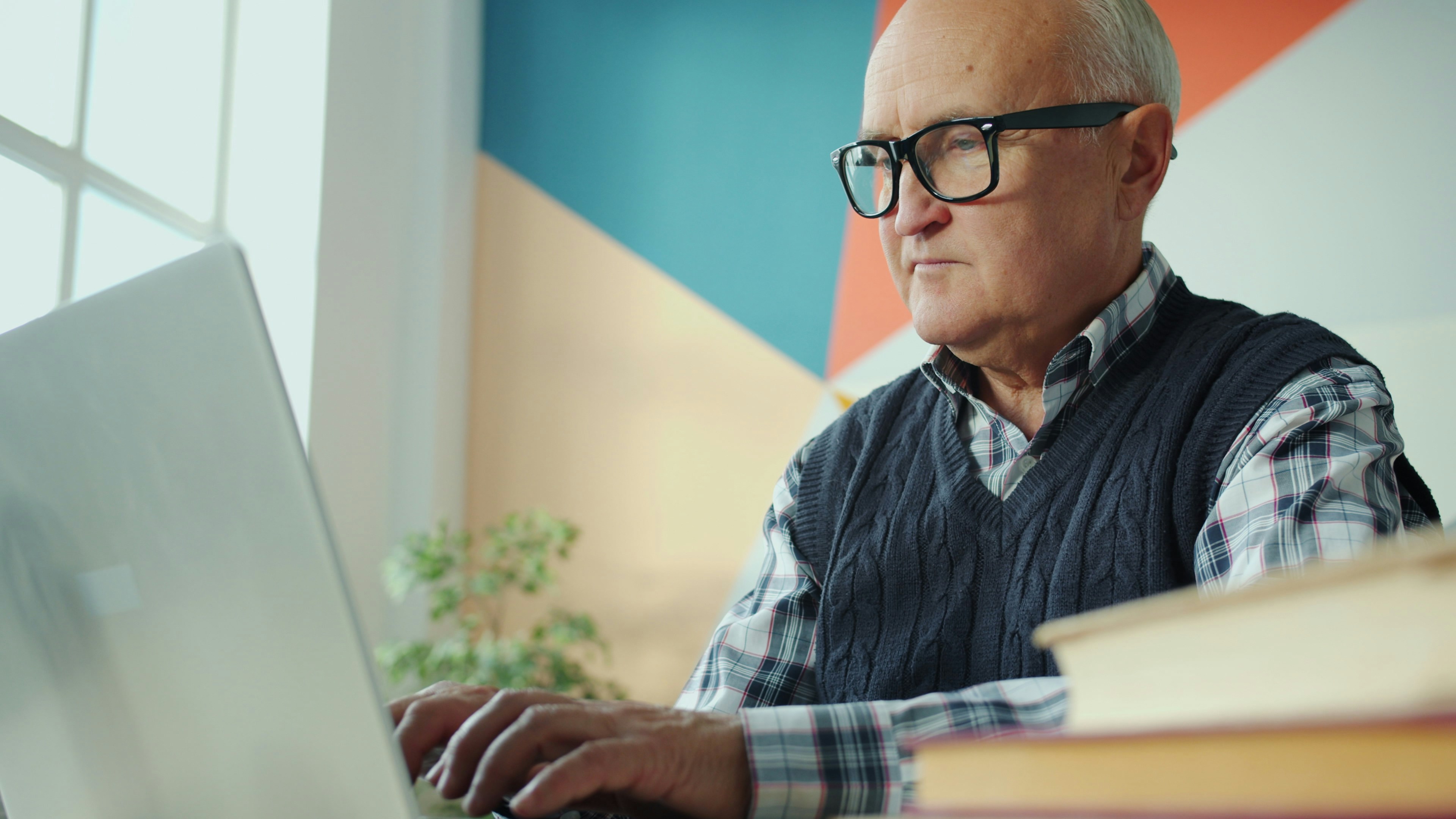Elderly man with glasses using a laptop