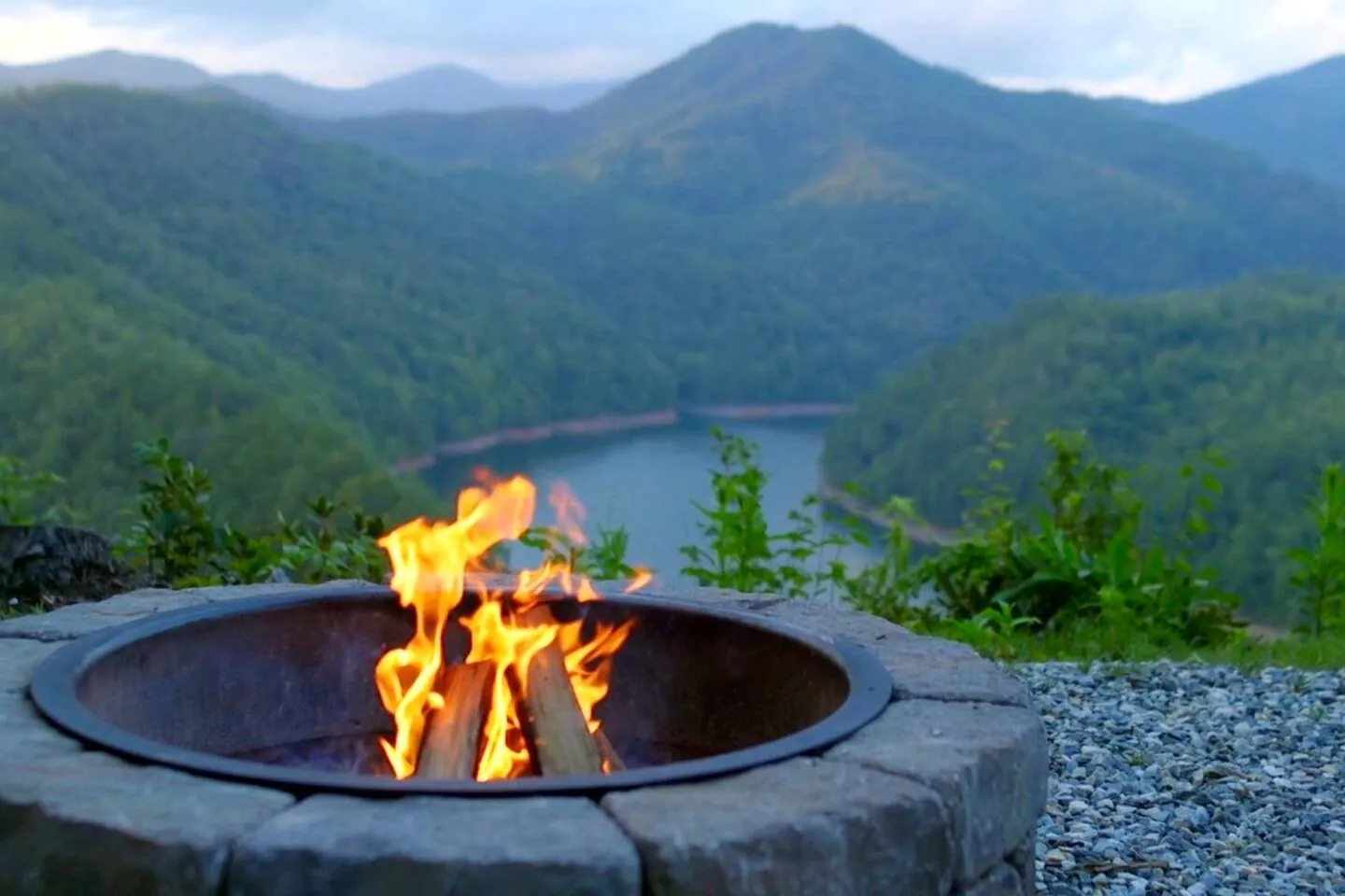Lit fire pit on the ridge with Fontana Lake and green mountains behind