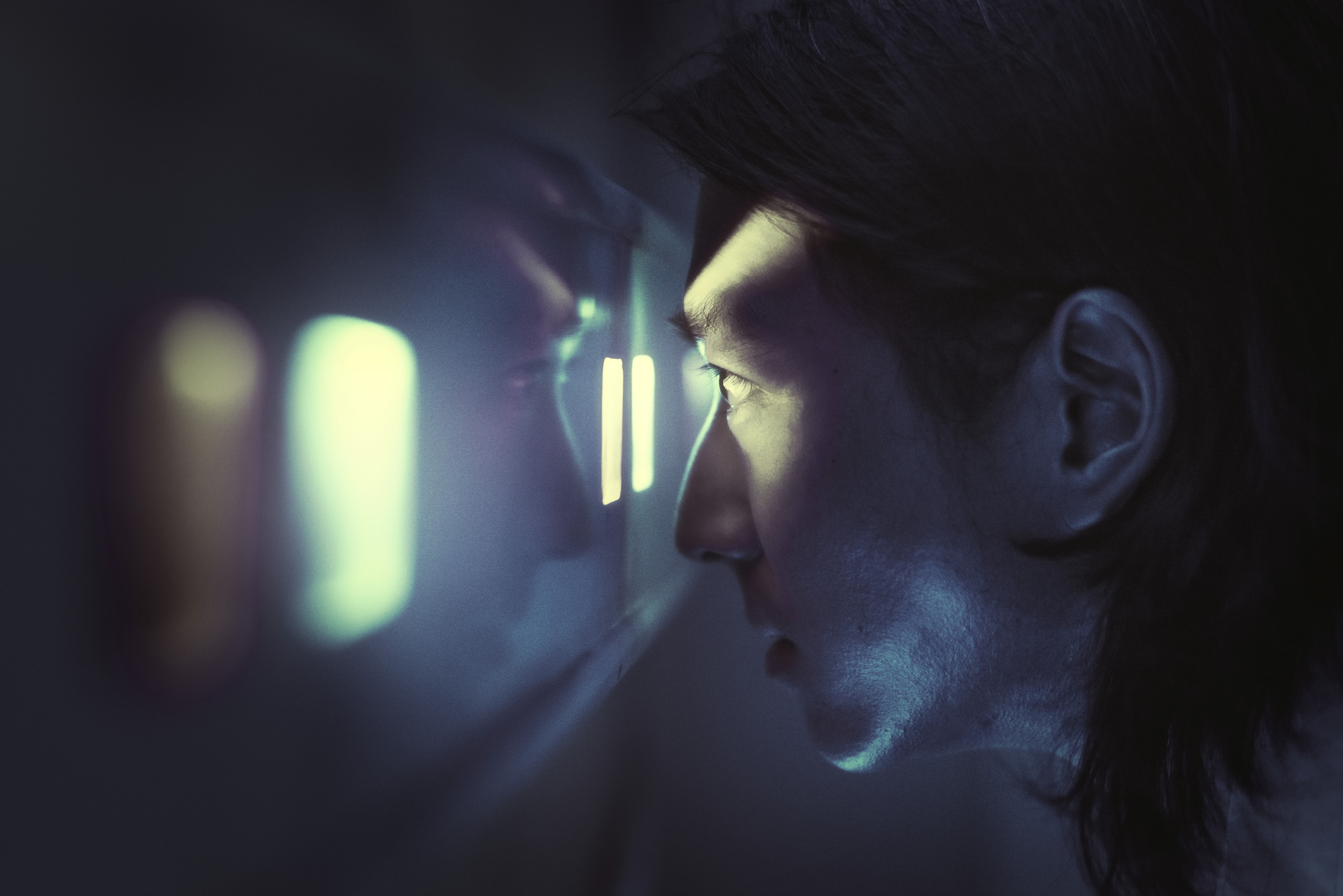 Person looking into a glowing window in blue light.