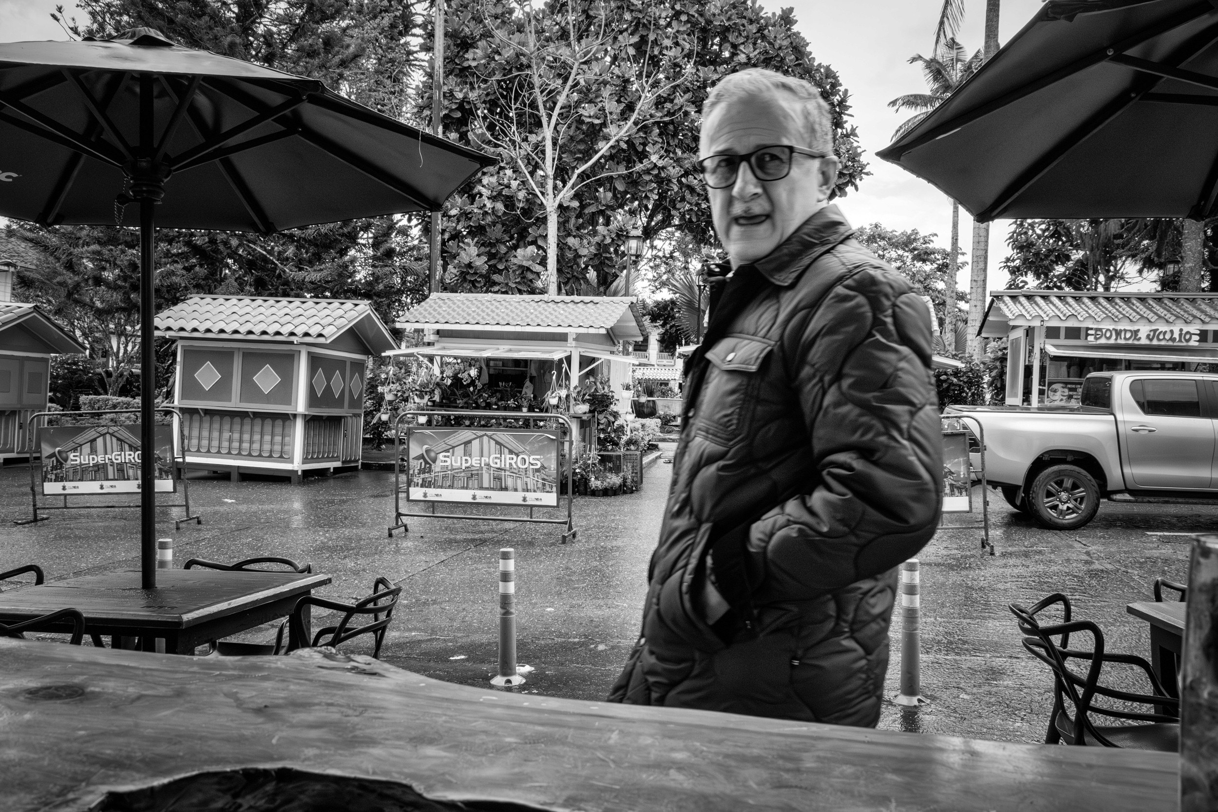 Rainy street scene with people passing by a bar window.