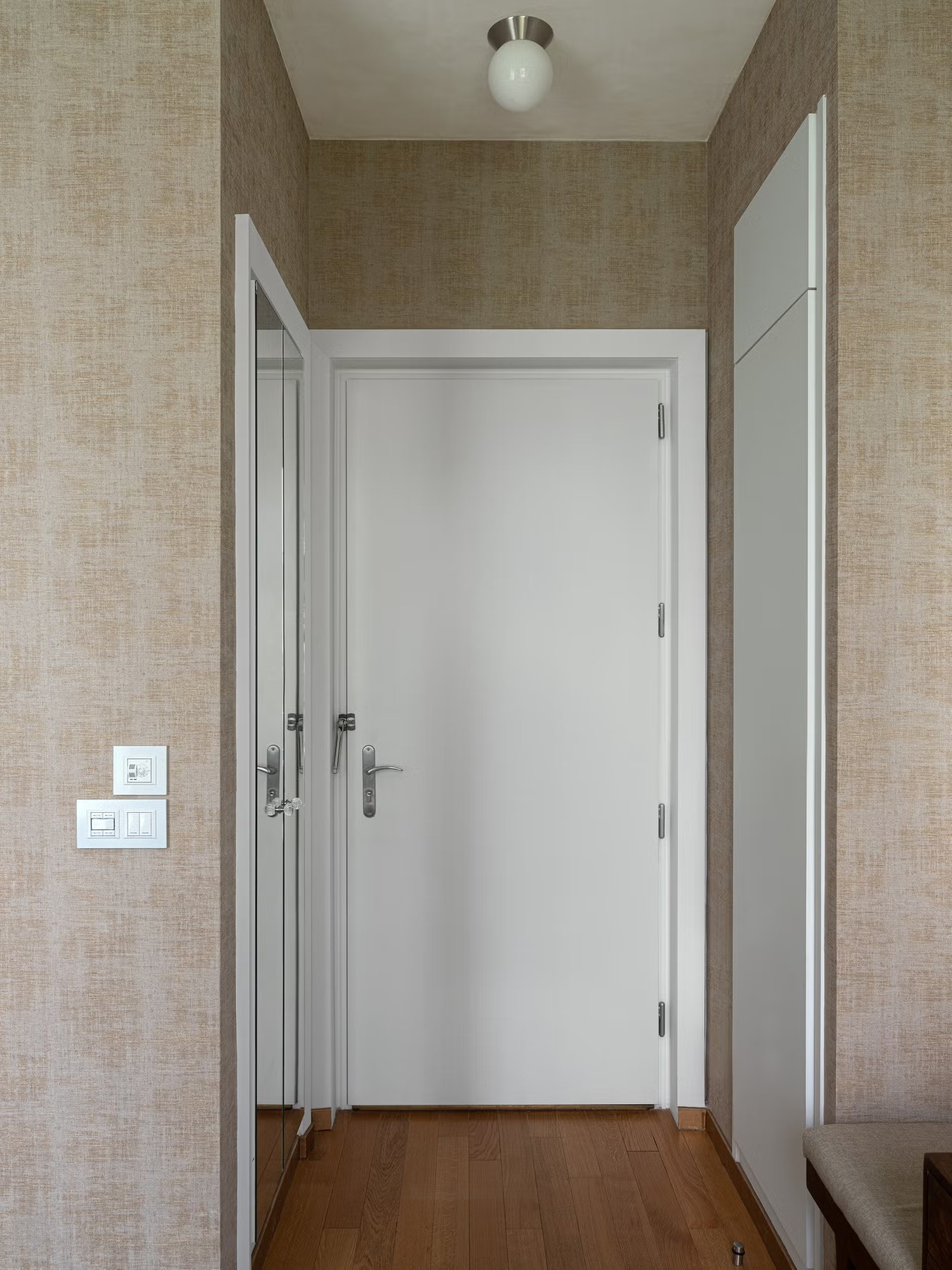 Porte intérieure blanche minimaliste parfaitement intégrée dans une cloison décorée de papier peint texturé.