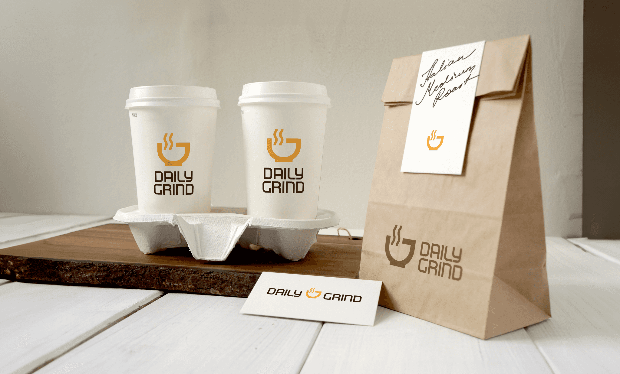 Two white coffee cups in a holder with a brown paper bag all displaying a unique logo