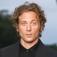 Jeremy Allen White in a black suit over a blurred background