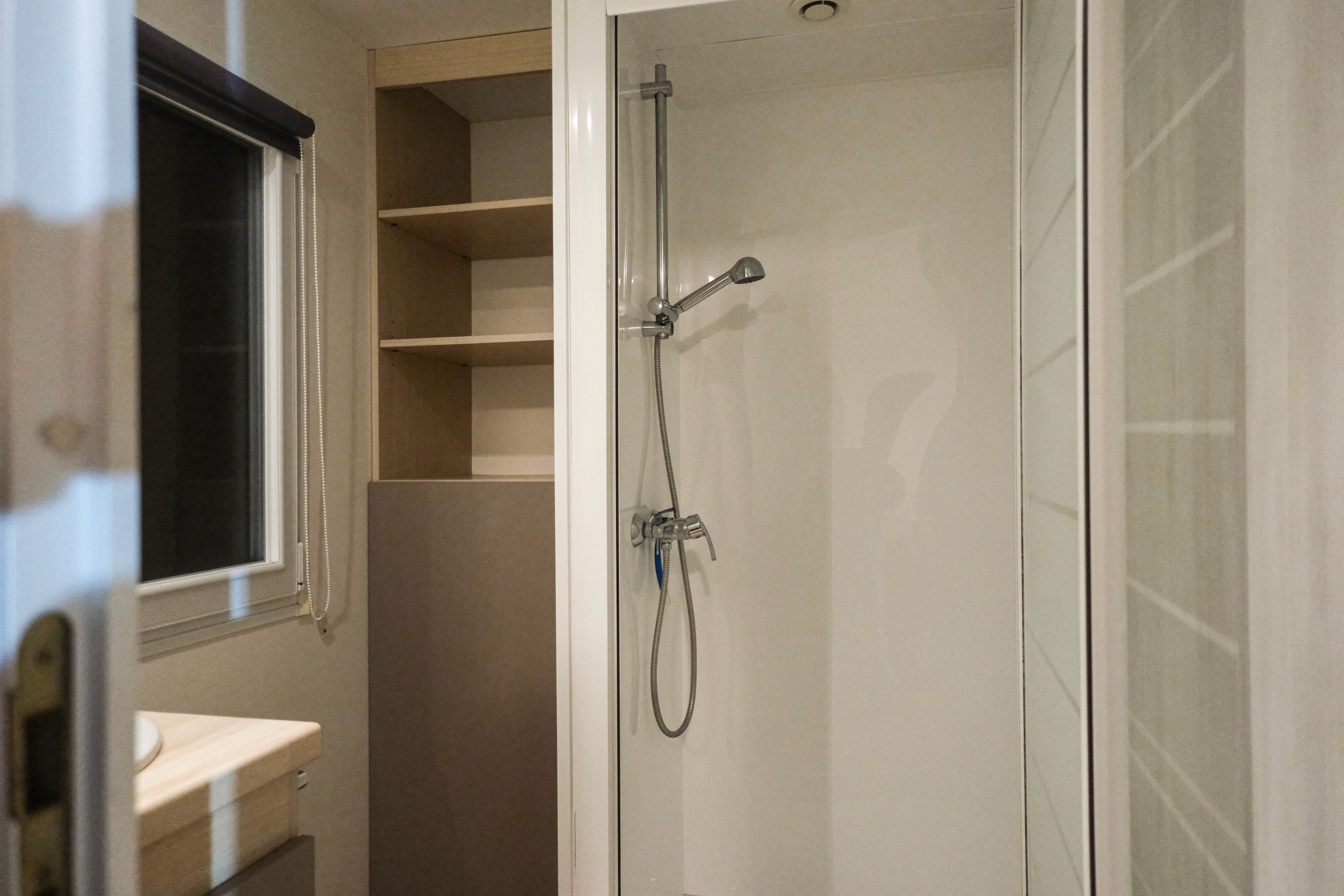 Beige upholstered bed with patterned pillows and ottomans